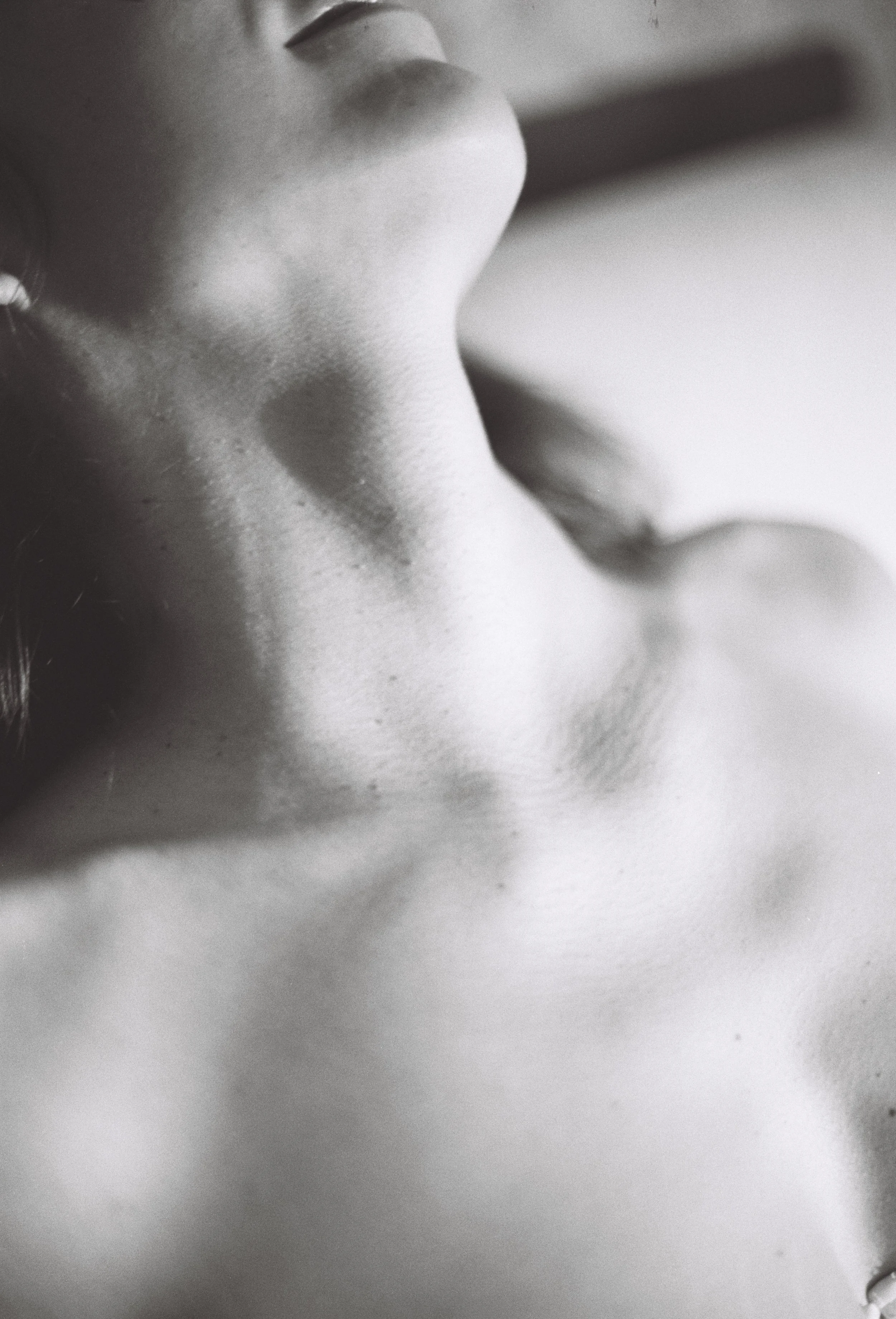 Close-up of a woman's face and shoulder in black and white, focusing on her nose, lips, and neck.