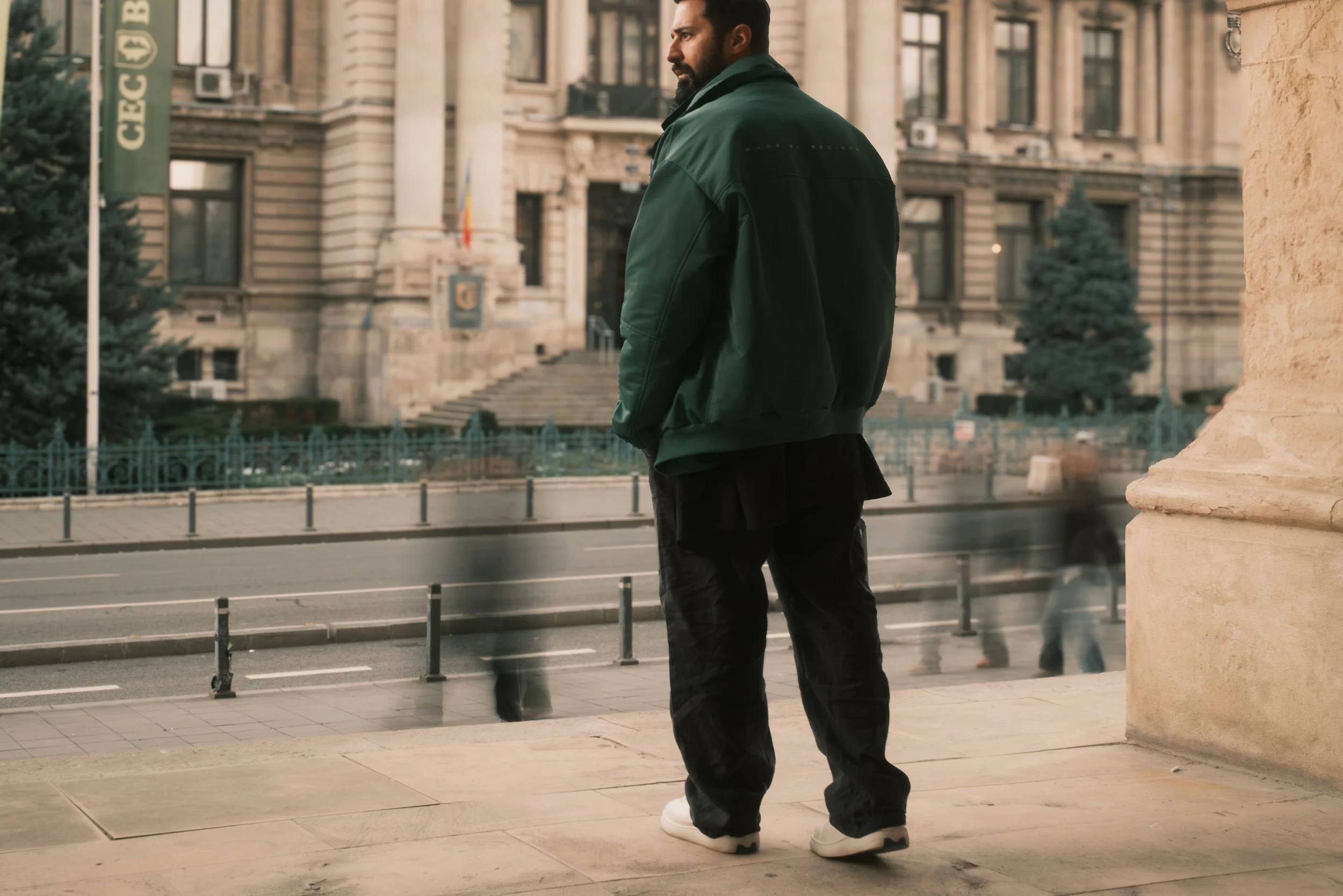 Ahmed Hatem on a city sidewalk in Bucharest, separated from the background by shallow depth of field, with movement unfolding behind him.
