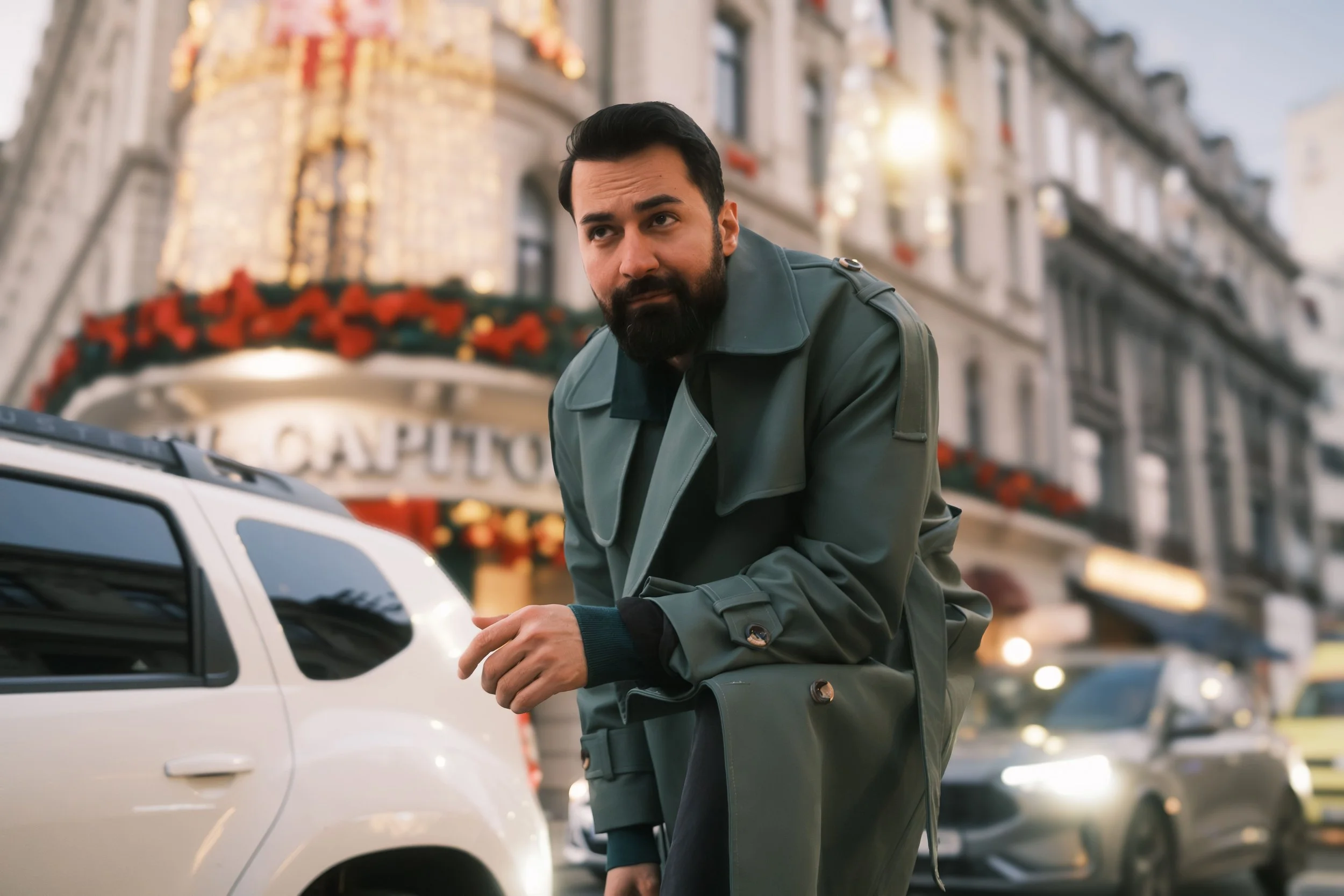 Ahmed Hatem leaning on a white car in the city, framed by reflections and urban light.