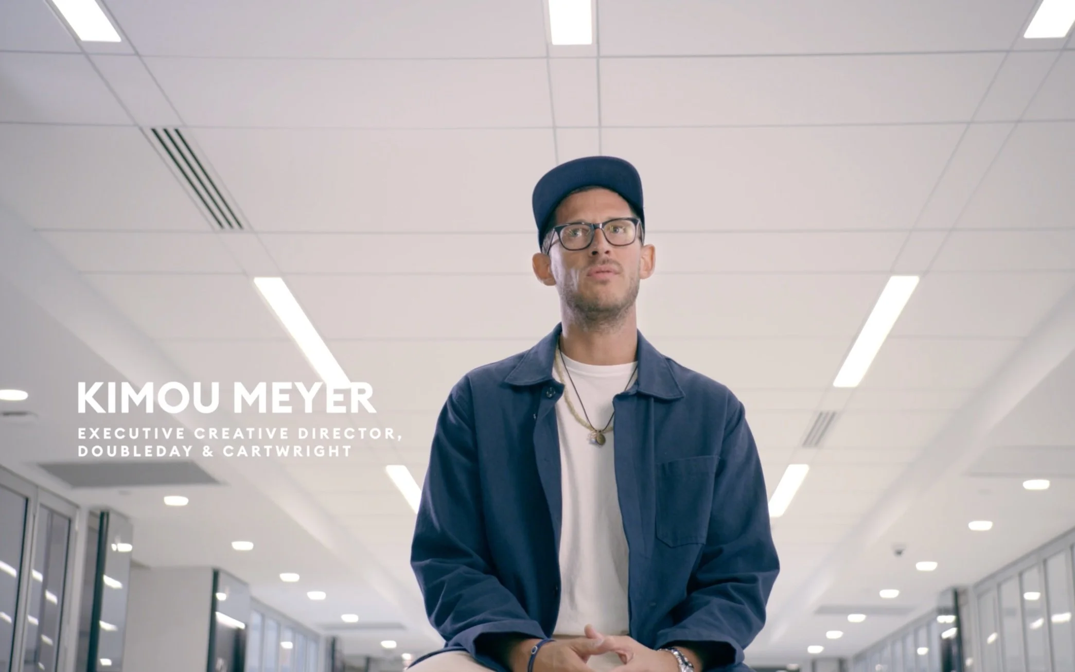 Kimou Meyer, executive creative director, standing in a modern, brightly lit office with white ceiling and large windows.
