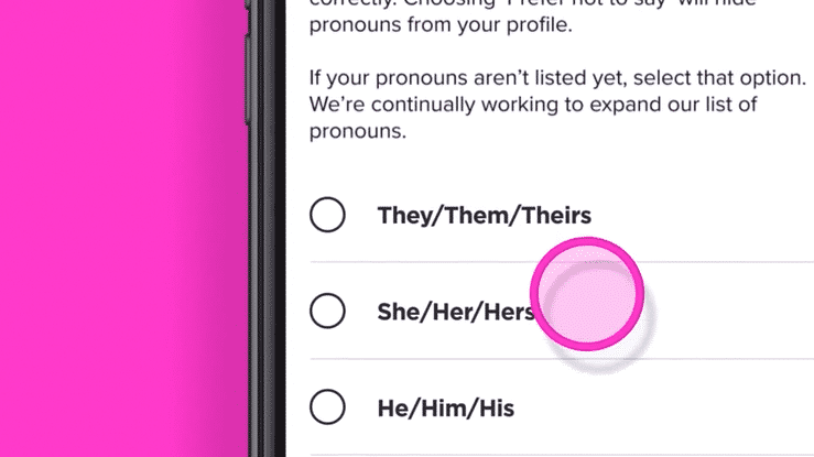 Close-up of a smartphone screen showing a voting or selection form with multiple-choice options for pronouns, including They/Them/Theirs, She/Her/Hers, and He/Him/His, with the She/Her/Hers option circled in pink.