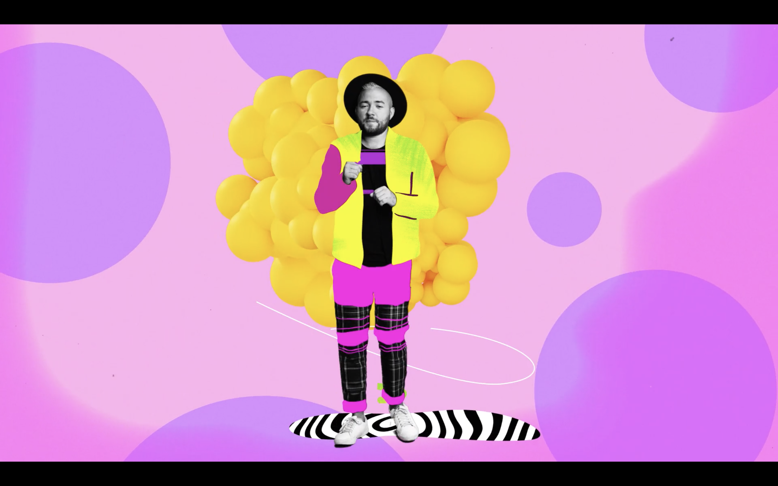 Person with a black and white face, wearing a bright yellow jacket, pink shorts, plaid pants, white shoes, and a black hat, standing against a colorful abstract background with yellow spheres, purple circles, and pink and purple hues.