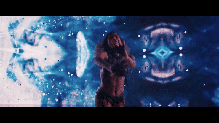 A woman in lingerie stands in front of a digital, kaleidoscope-like background with abstract blue and white light patterns.