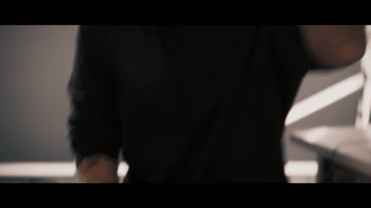 Close-up of a person wearing a black shirt, with part of their arm and shoulder visible, in an indoor setting.