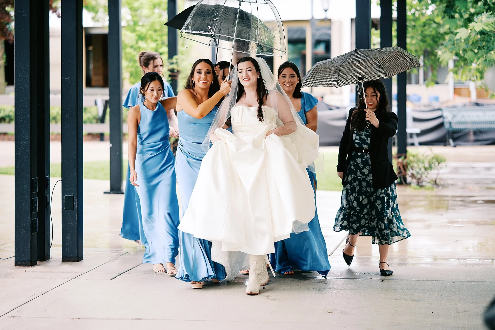 Bride being escorted to getting ready under umbrellas at Fasig-Tipton wedding in Lexington, KY
