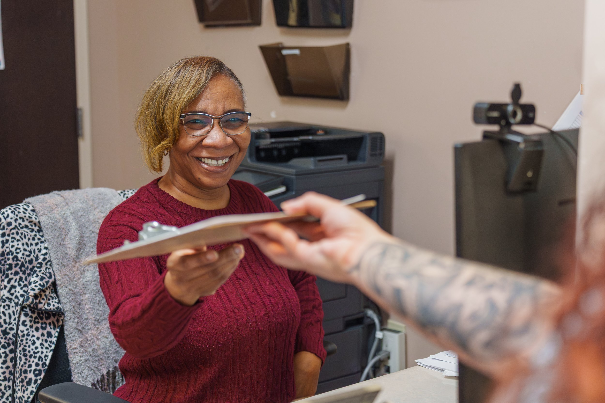 Staff handing new patient paperwork to fill out at the H&V front desk.