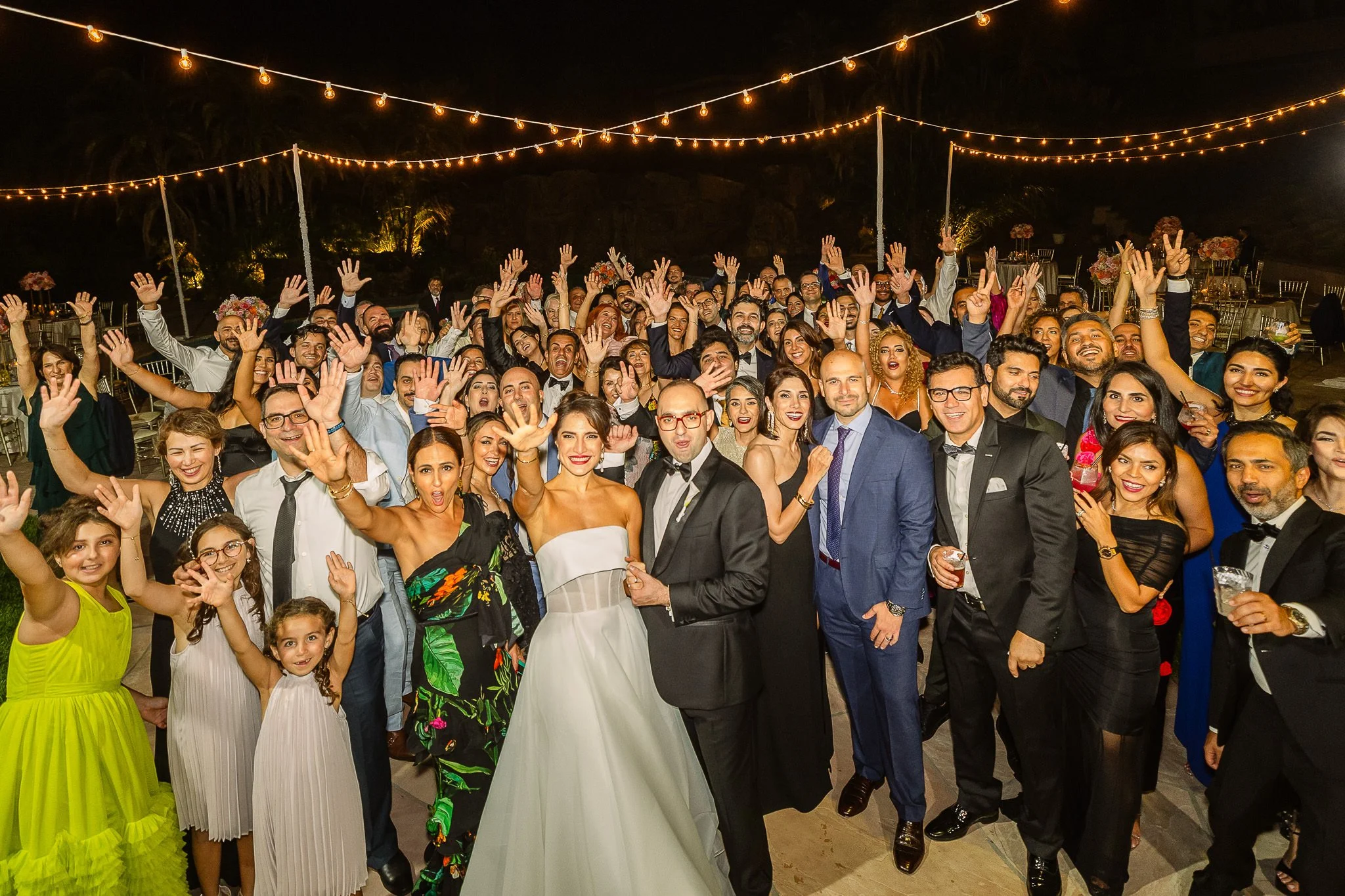 bride and groom taking fun photo with large group on their wedding day