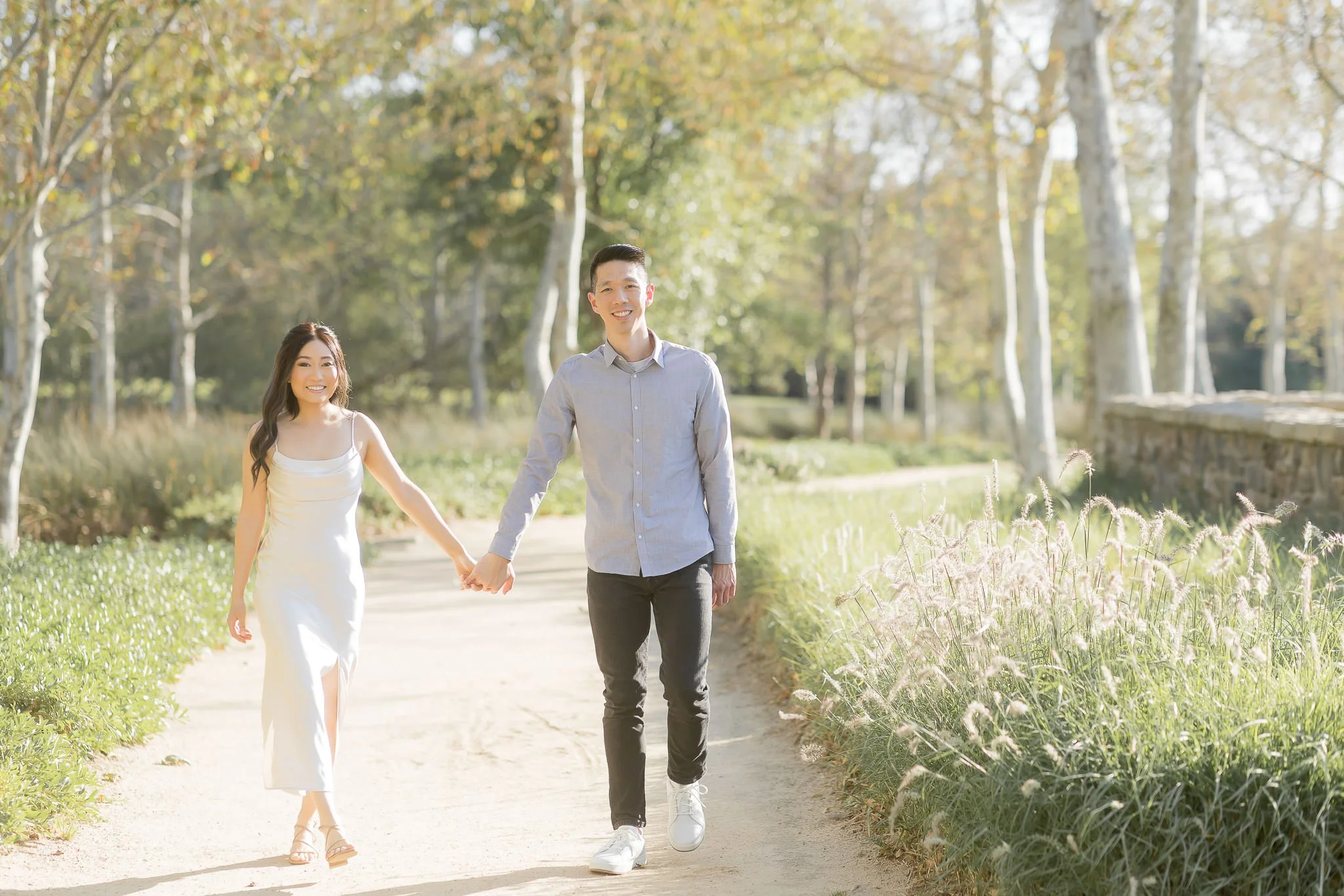 Professional photographer guiding engaged couple through natural poses during Orange County engagement session