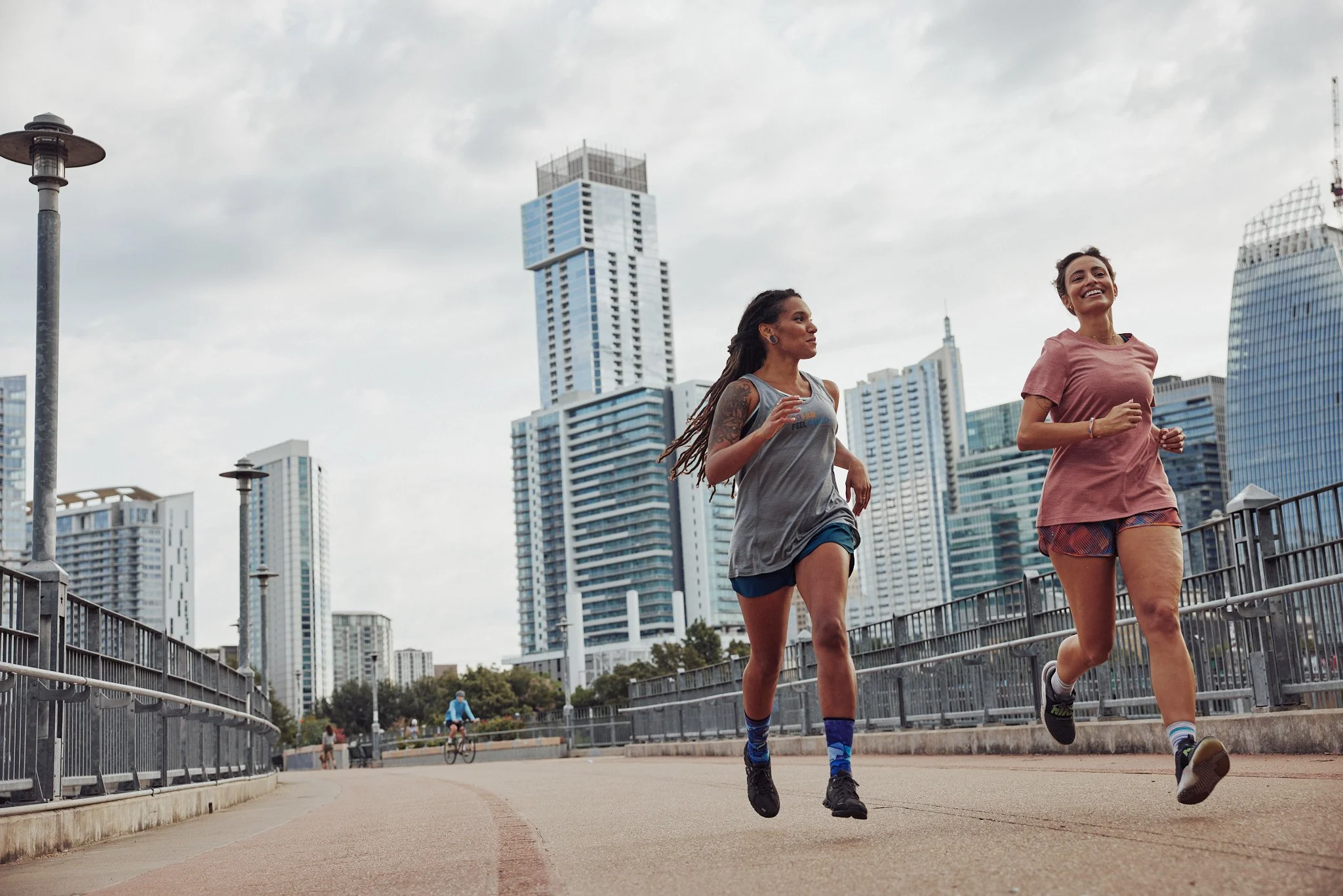 Two women running on a bridge toward downtown Austin, Smartwool Spring 2021 campaign, photography by Dag Larson