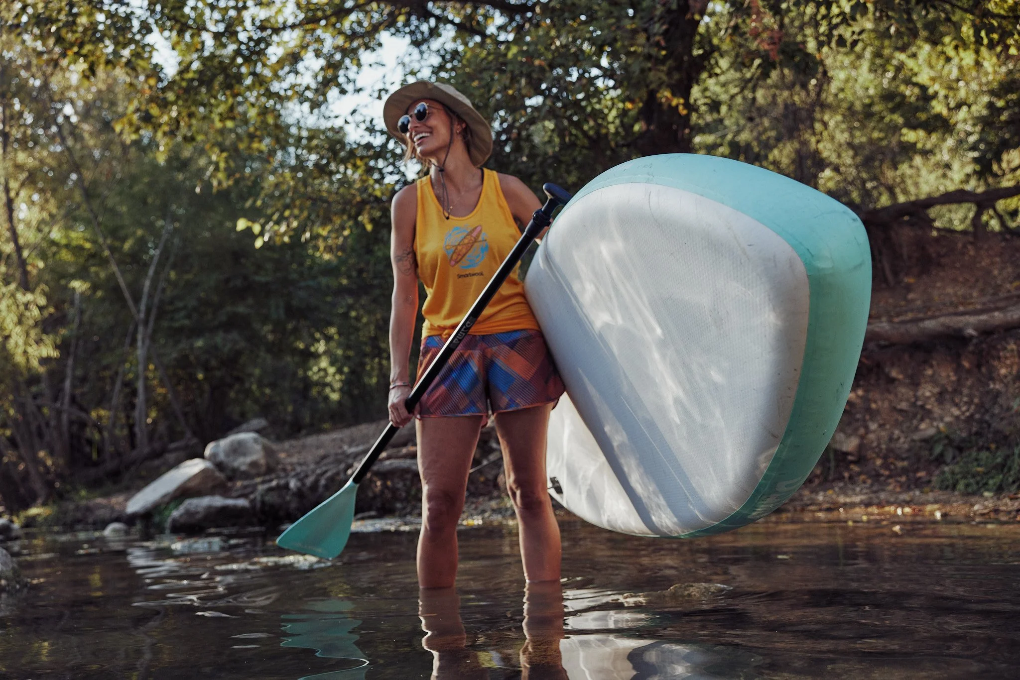 Woman carrying a paddleboard to the river in Austin, Smartwool Spring 2021 campaign, photography by Dag Larson