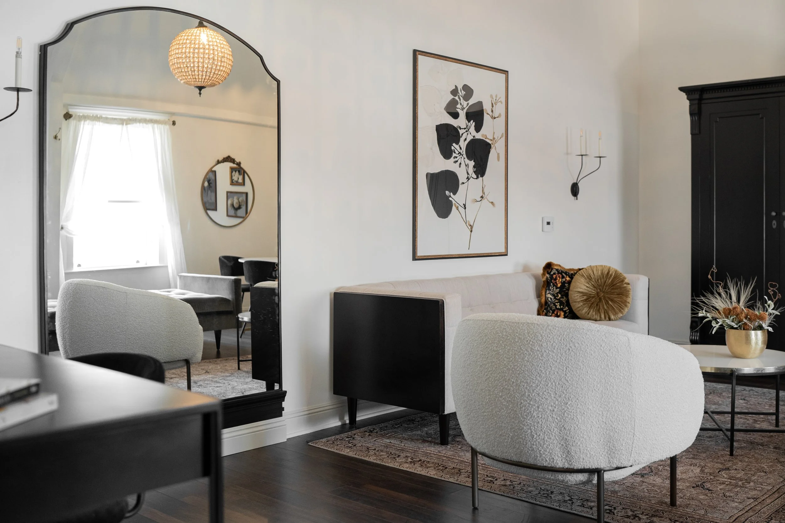 Elegant black and white retreat area in the Altar Long Beach Suite, showing comfortable seating and an artistic mirror detail. Ideal for private client preparations.