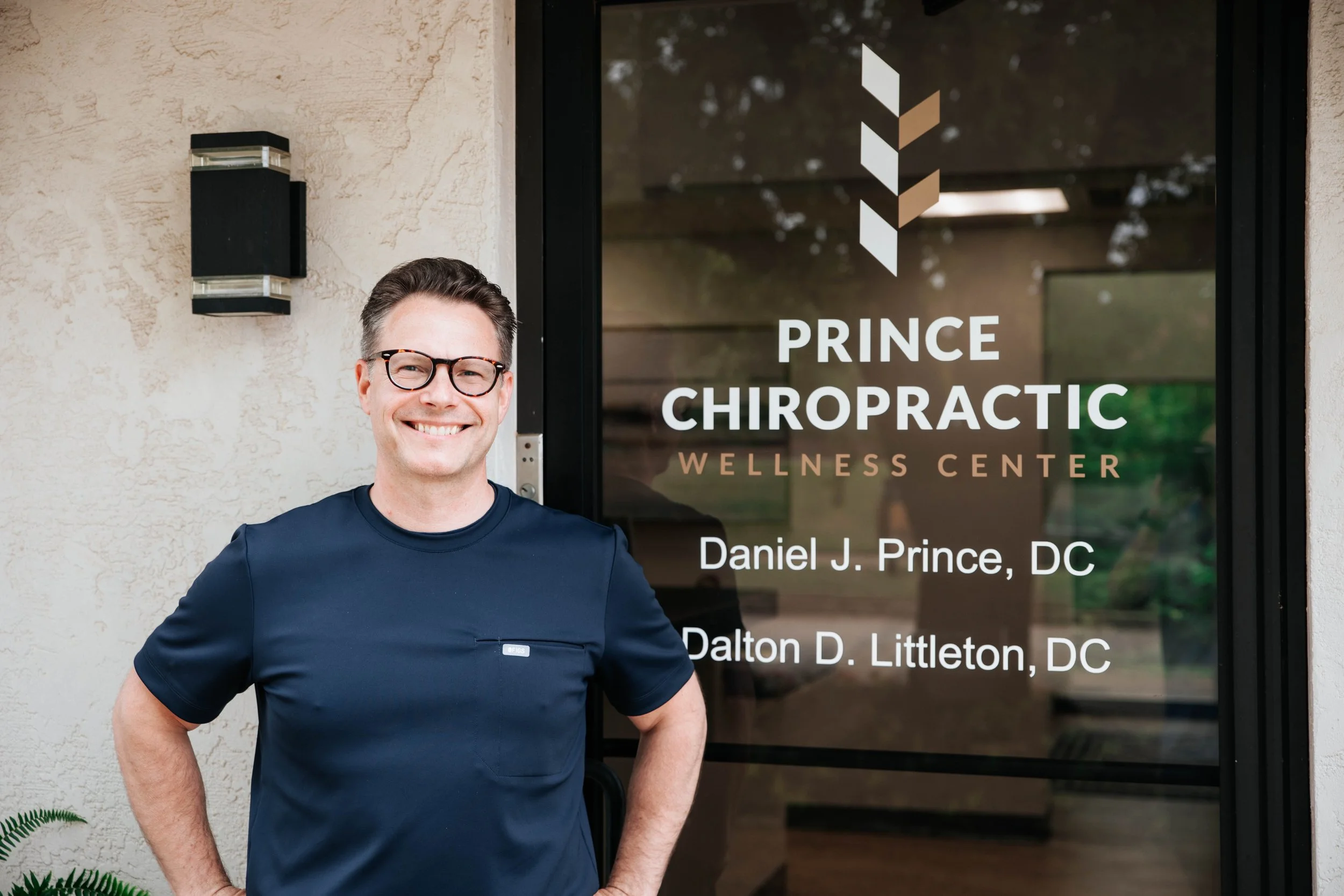 Dr. Prince in front of clinic door with logo and information