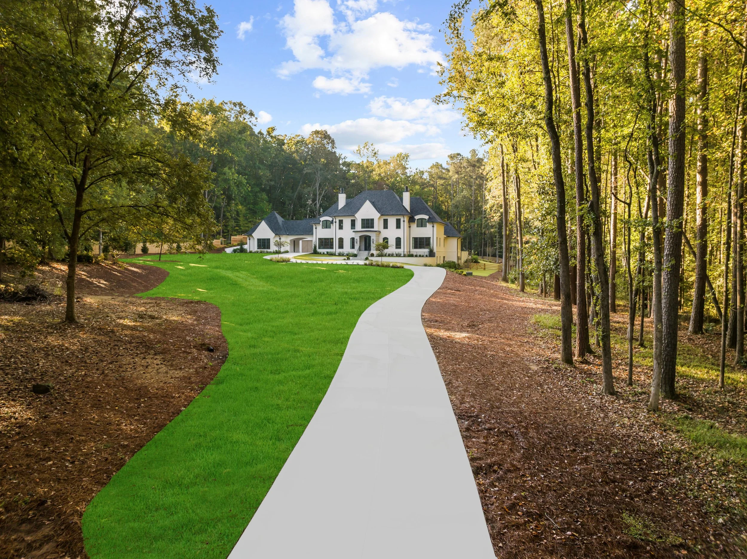 A large white house with dark roof and multiple chimneys at the end of a winding concrete driveway, surrounded by lush green grass and tall trees, with a partly cloudy sky above.