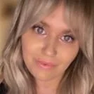 Close-up of a woman with blonde hair and purple eyes looking at the camera