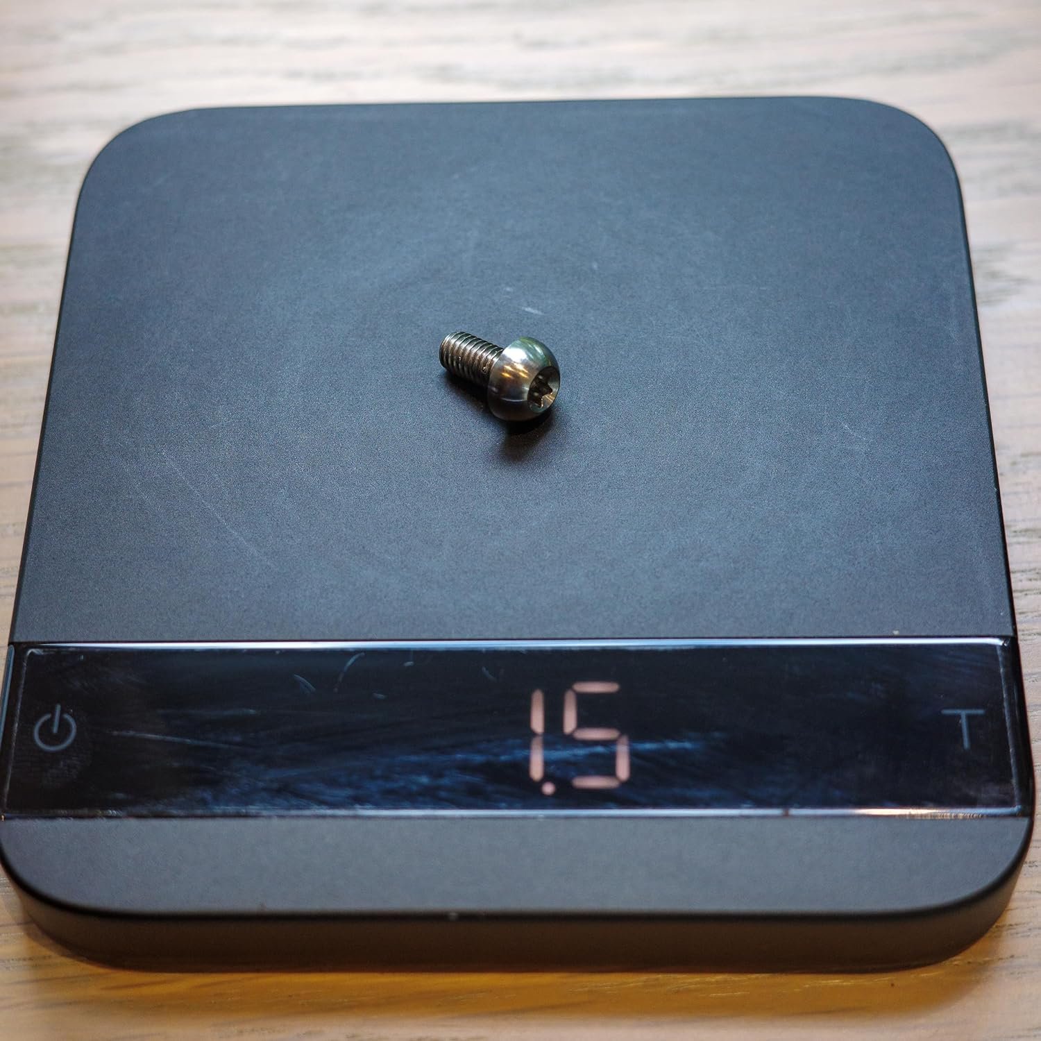 image of the titanium screw on a scale, showing 1.5g