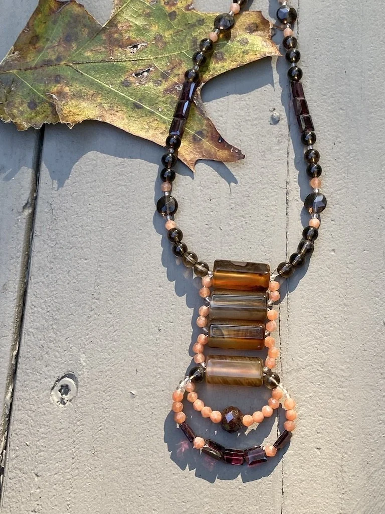 Hexagon-shaped carnelian stones float together with cascading peach moonstone, garnet and smokey quartz on a 24 inch smokey quartz necklace. unique and special necklace
