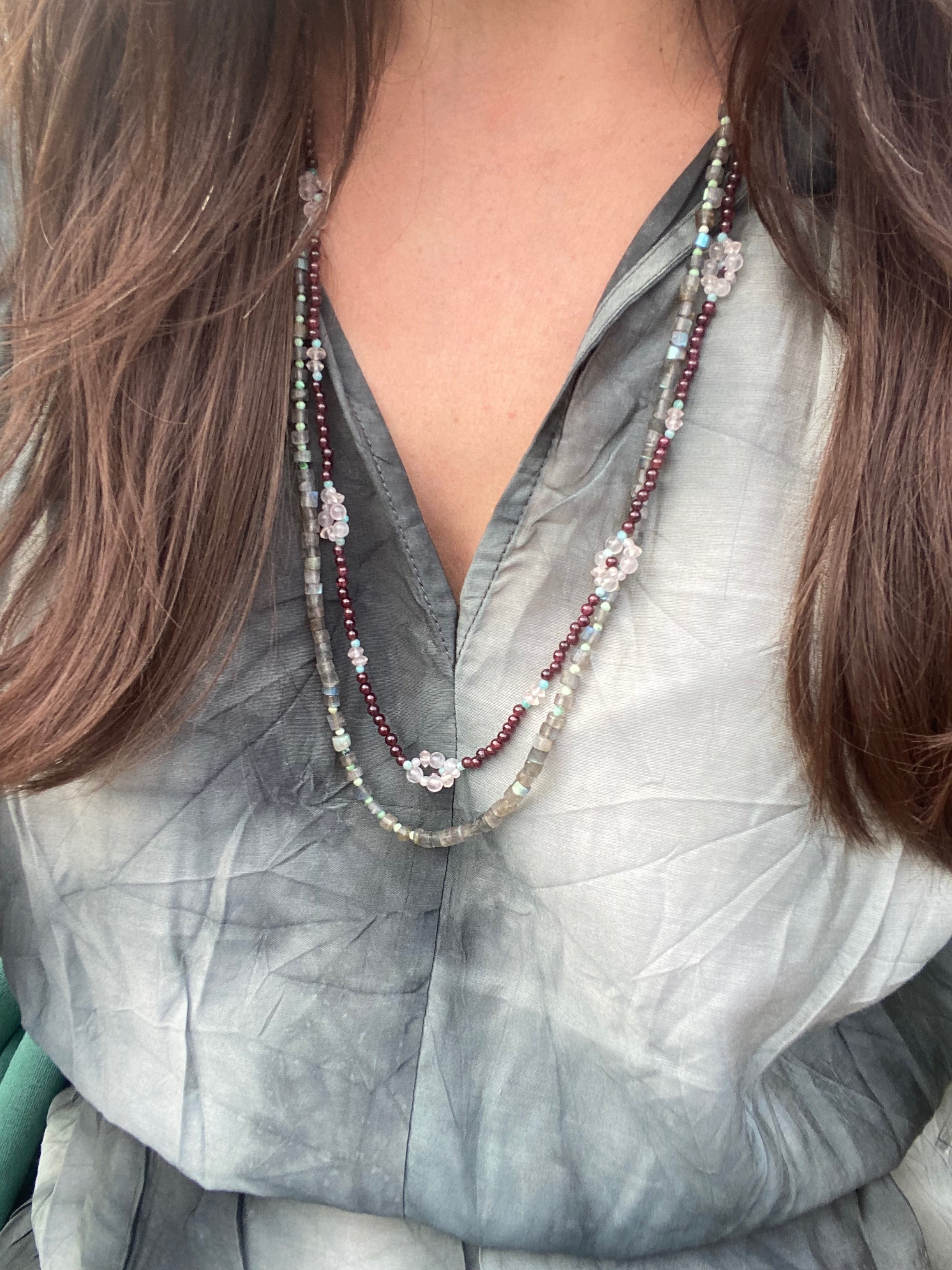 Apatachi handcrafted bohemian necklace with Rose Quartz Wildflowers on a long necklace of Garnet gemstones with Amazonite and pyrite in this beautiful necklace worn on dark gray dress