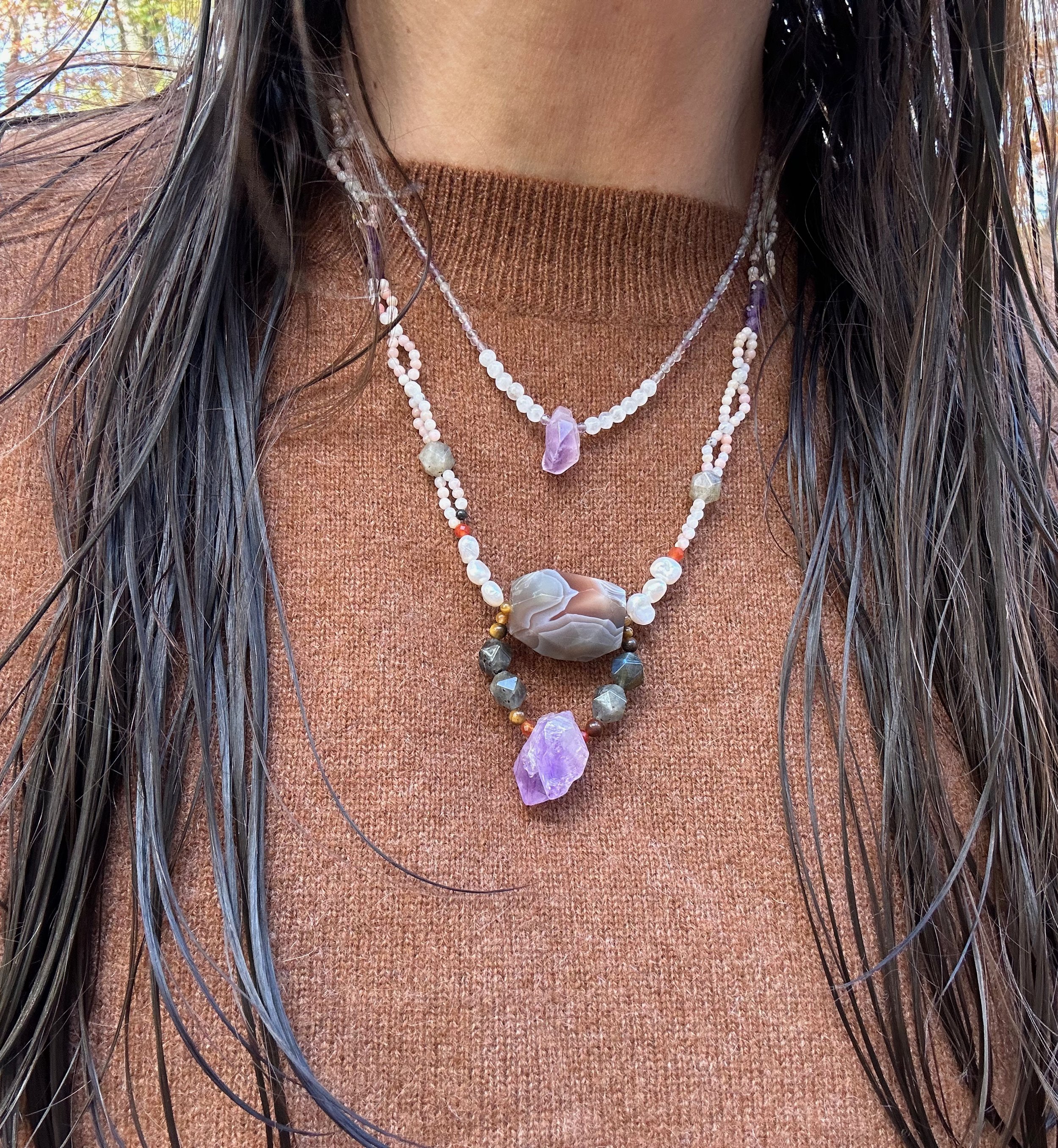 Apatachi handmade necklace. Bold centerpiece with faceted amethyst and agate on a woven pink opal necklace on a caramel brown cashmere sweater