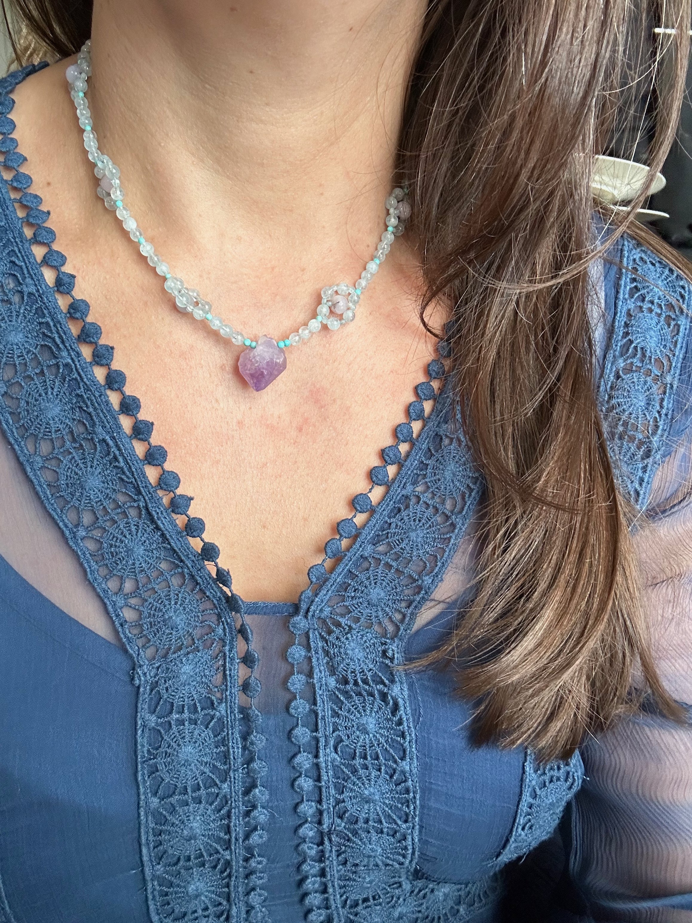 Worn with cobalt blue dress for a wedding, this raw faceted Amethyst stone dangles from a unique gemstone necklace of aquamarine and turquoise wildflowers to show off its organically faceted shape.