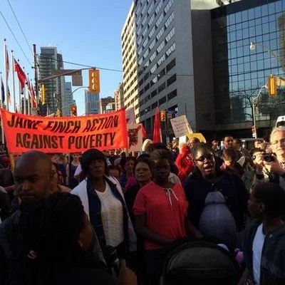Photo of people at a protest with a banner that says Jane Finch Action Against Poverty