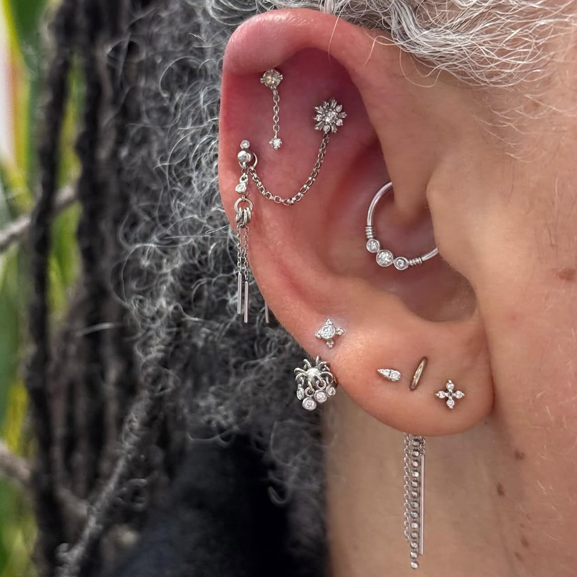 An ear with a mix of white gold and diamond jewelry with chain accents.