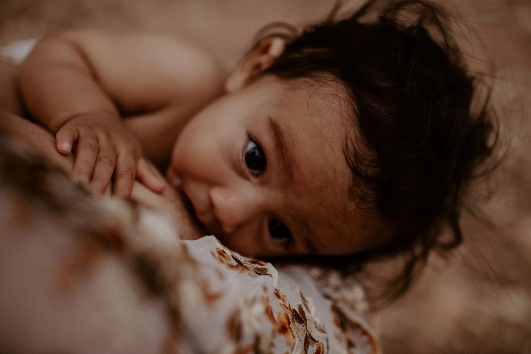 a baby feeding at their mother's breast
