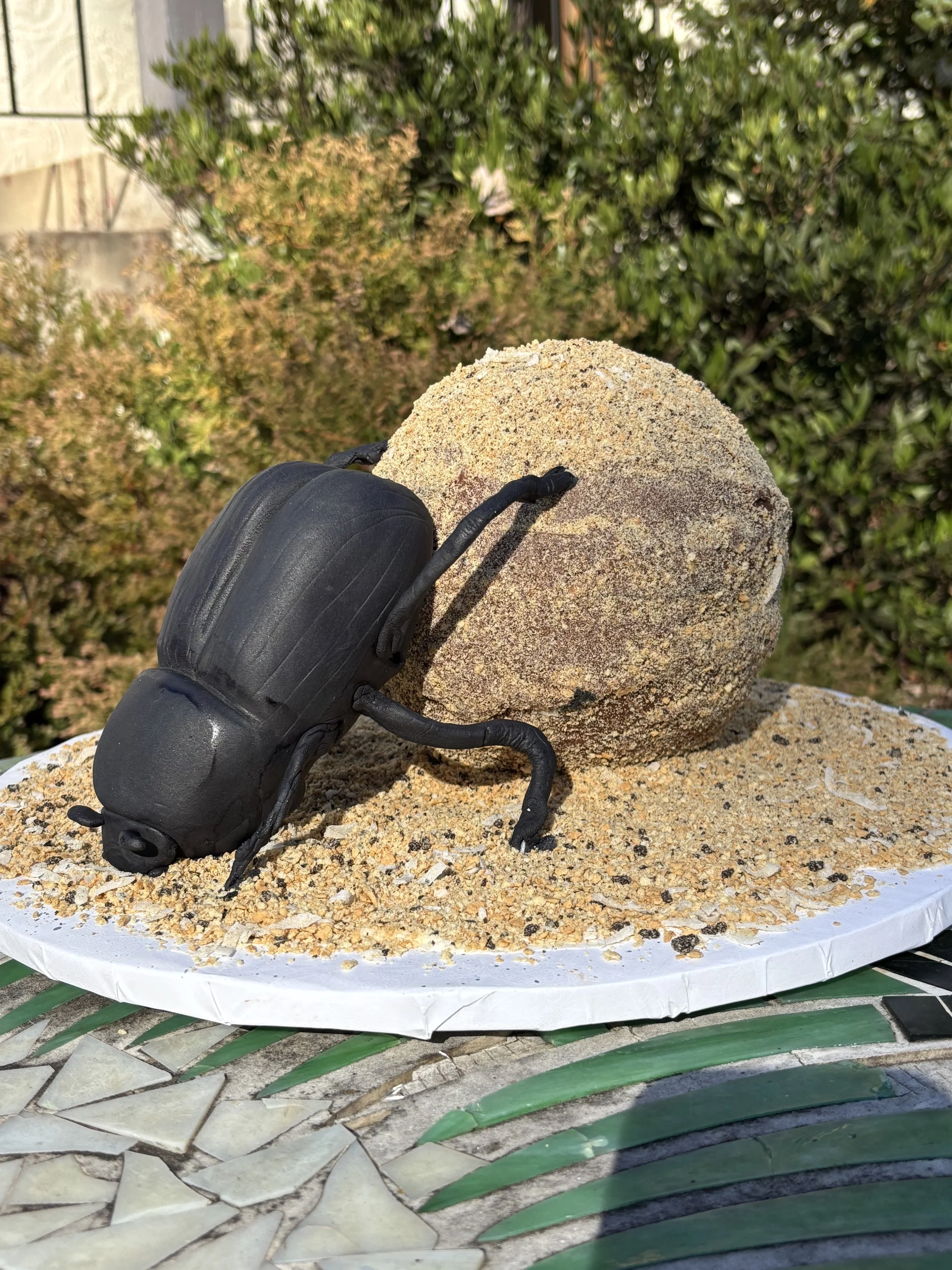 Black dung beetle cake rolling a ball of dung that is entirely edible, chocolate cake with cookie crumbs