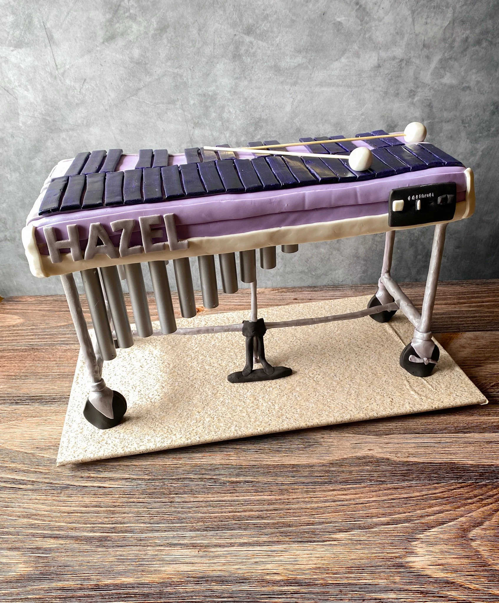 Cake decorated as a xylophone with black keys, white mallets, and the name 'Hazel' on the side