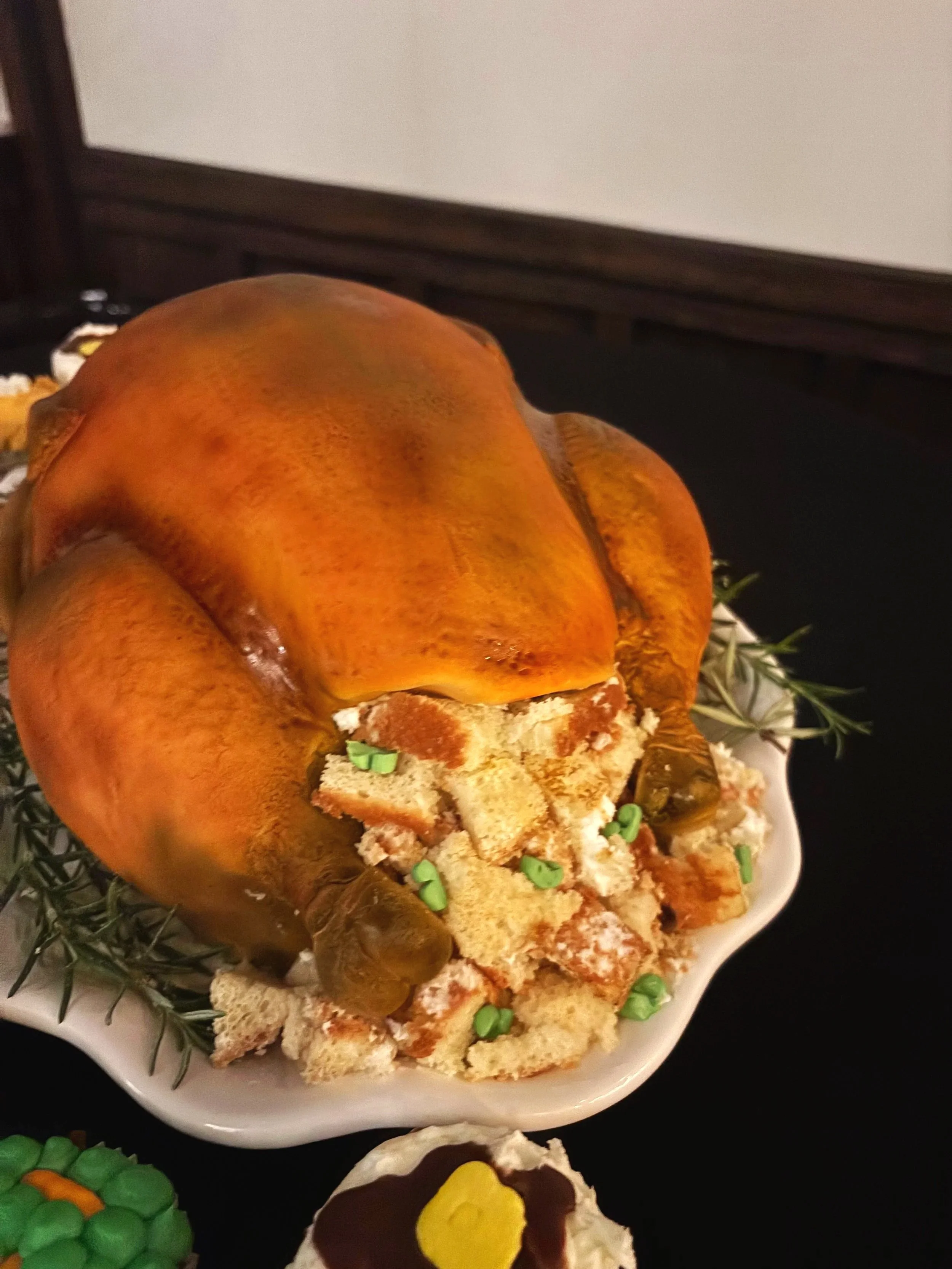 Close-up of a hyper-realistic roasted turkey cake by Artful Cakery by Julie, featuring golden hand-painted “skin,” edible stuffing made from cake pieces, and fresh herb garnishes. Custom sculpted Thanksgiving-themed cake created in Flowery Branch, GA