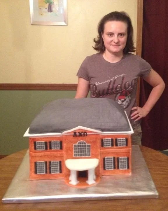 Young woman standing next to a cake model of a sorority building