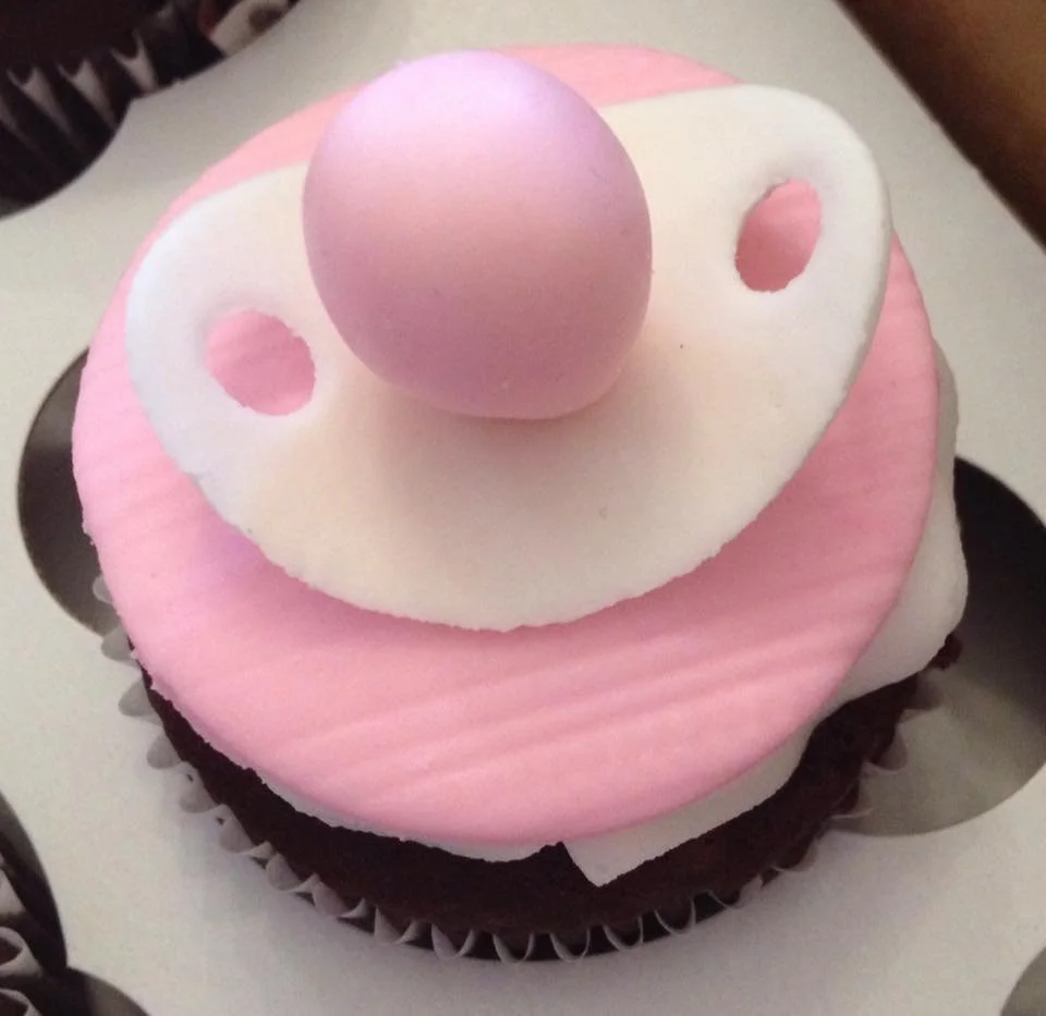Baby themed cupcake topped with fondant pacifier decoration