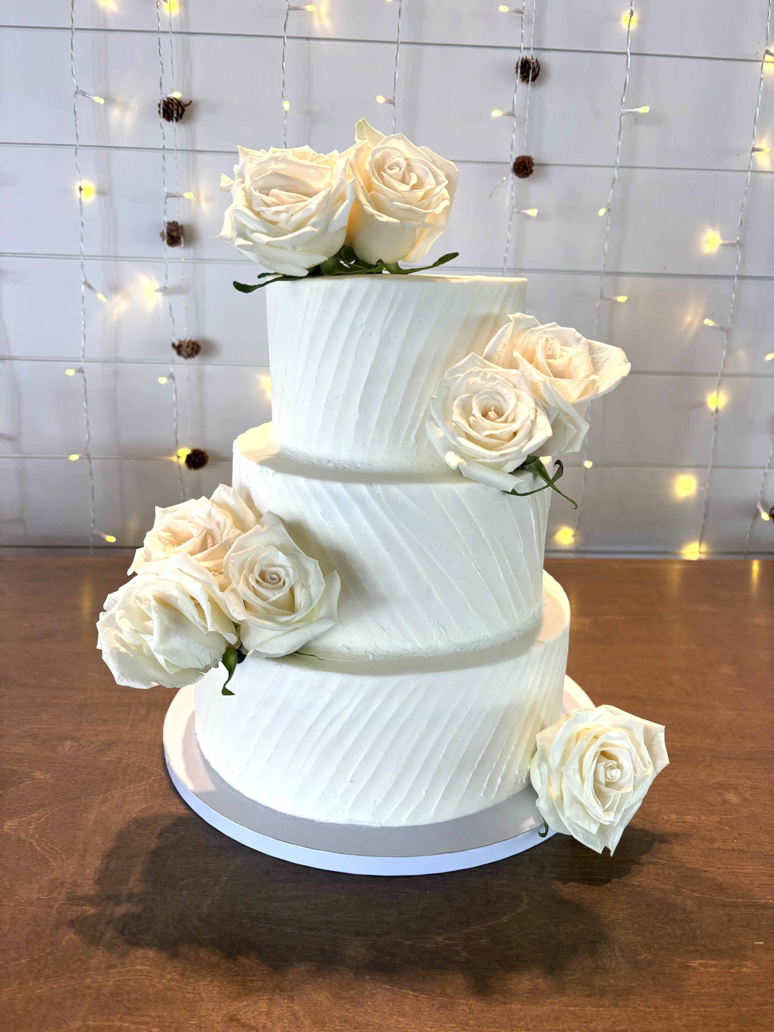 Three tiered textured buttercream wedding cake with fresh roses at wedding venue Stony Oak Farm in Jefferson, GA