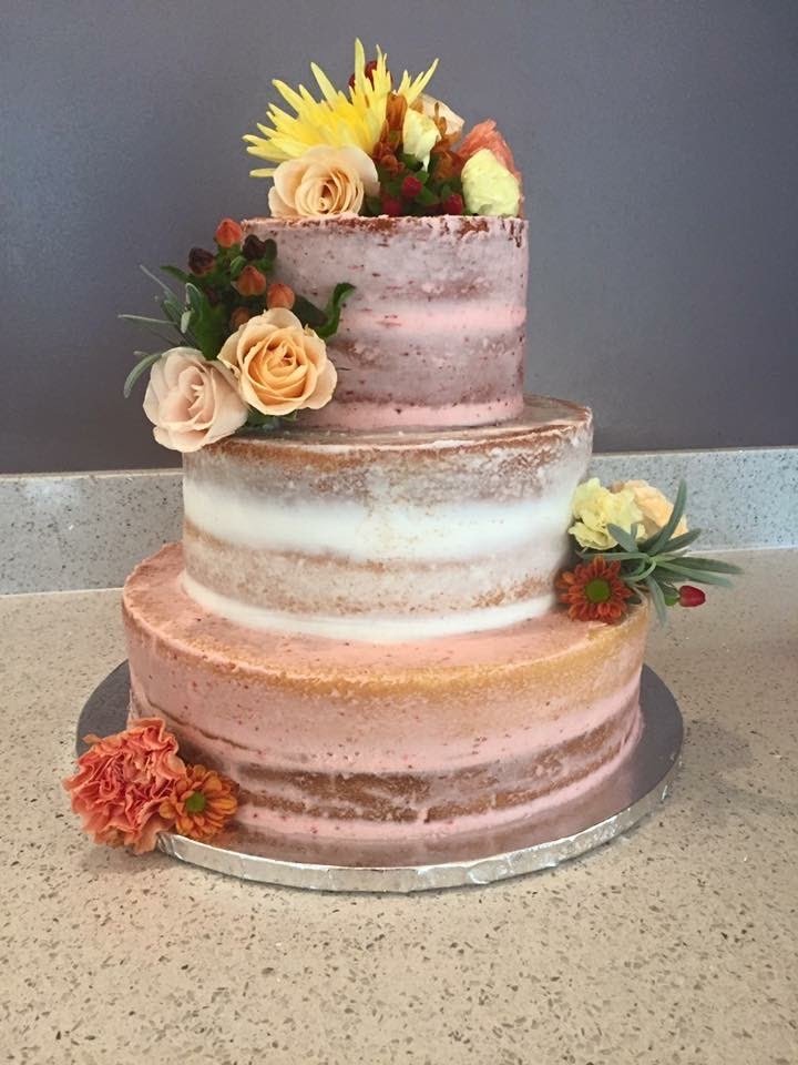 Three-tier semi-naked buttercream wedding cake with peach, pink, and yellow flowers for a wedding at Juliette Chapel in Dahlonega, Georgia.