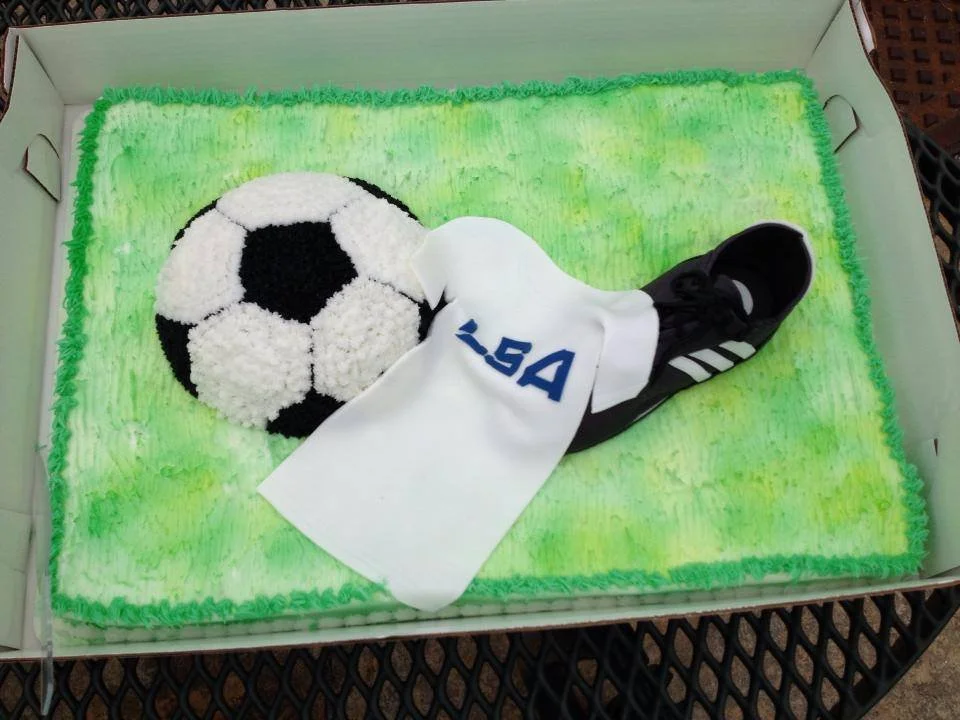 Soccer themed cake with sculpted ball, cleat, and jersey for athlete birthday