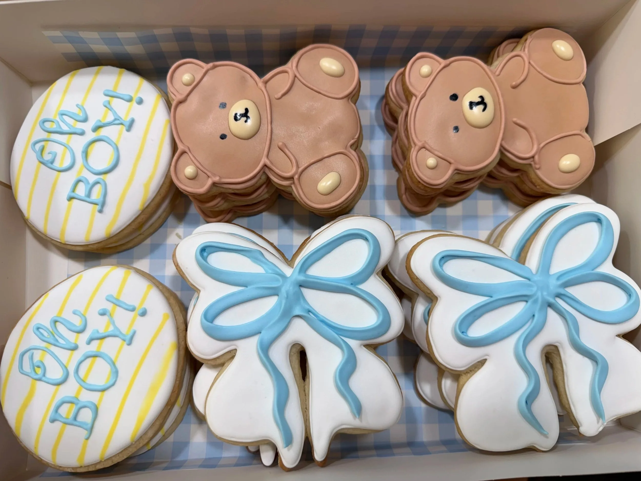 Box of decorated birthday cookies with a bear face, a white bunny, and a cookie with the words "Happy Day" written in blue icing.