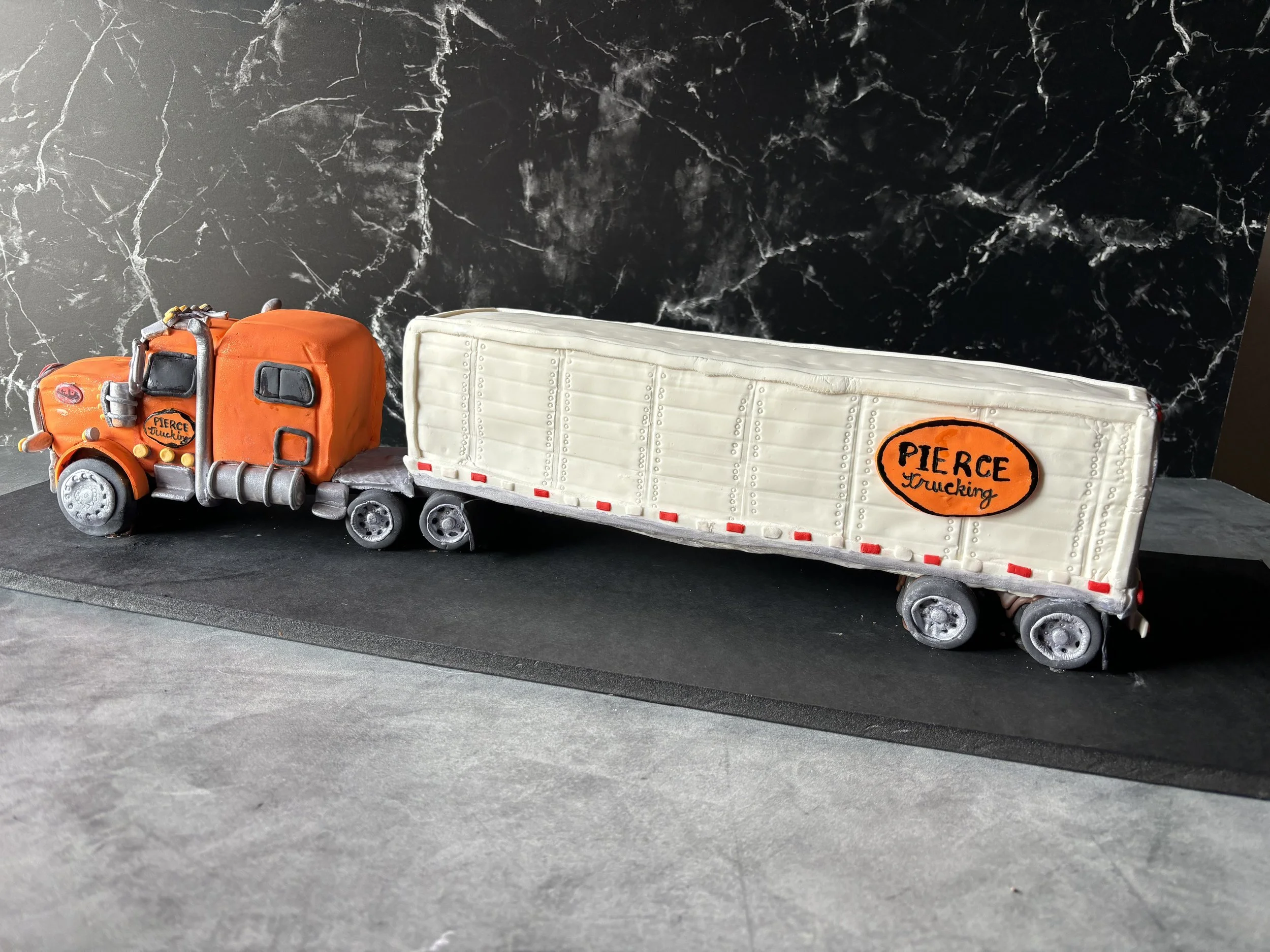 Realistic Peterbilt 18-wheeler truck cake sculpted with detailed cab and trailer.