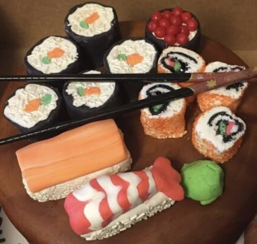 Realistic sushi and sashimi cake designed to resemble a wooden sushi serving board with chopsticks.