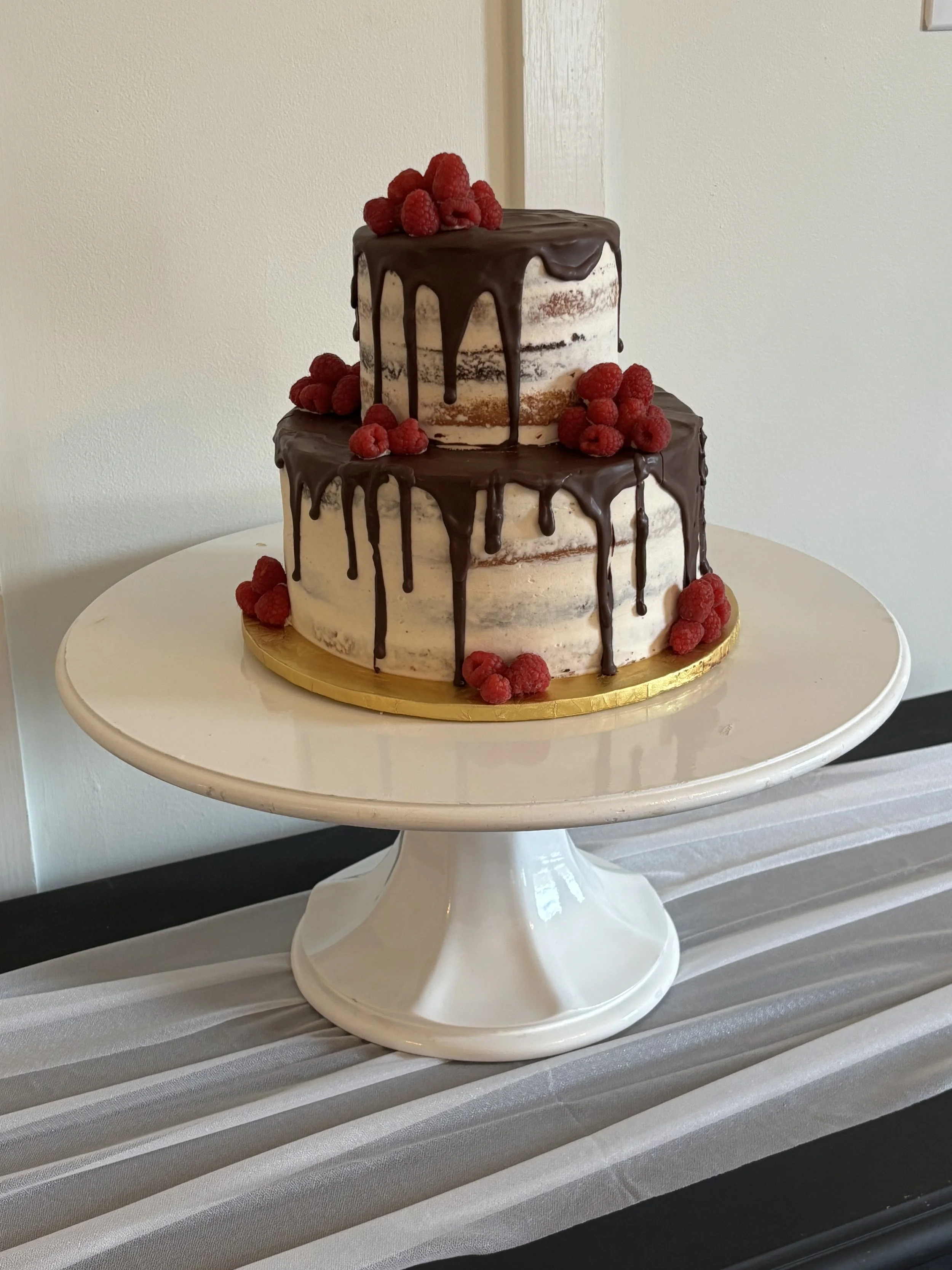Two tiered naked wedding cake with chocolate drip and raspberries for a wedding at Payne Corley House in Duluth, Georgia