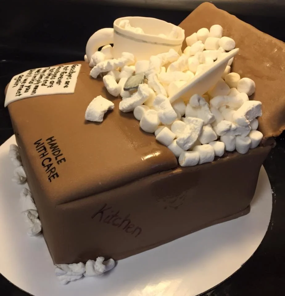 Sculpted moving box cake with packing peanuts and edible dishes inside