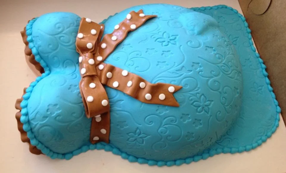 Blue sculpted pregnant torso cake with brown polka dot bow for baby shower