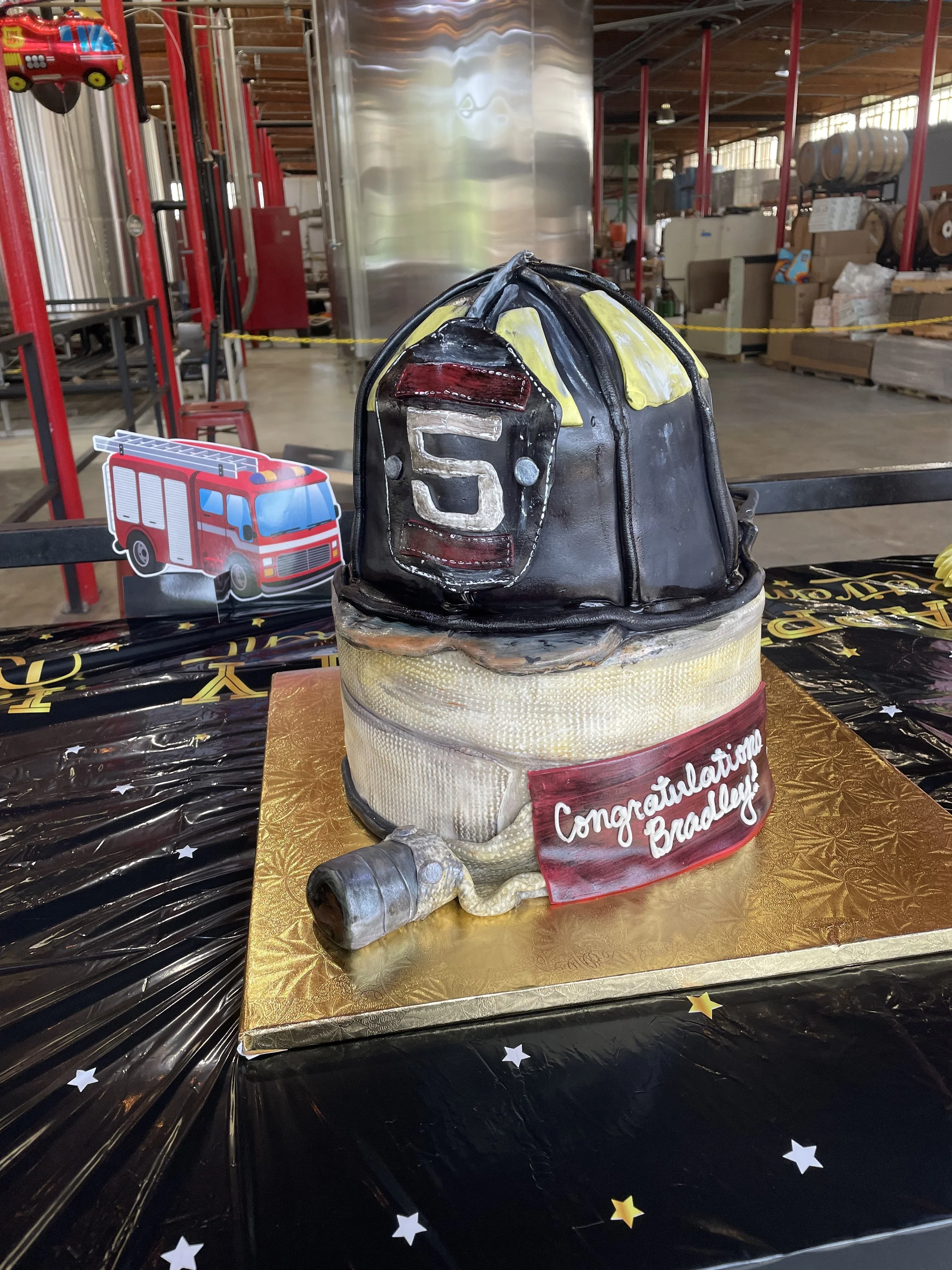 Firefighter retirement cake featuring a coiled fire hose and a detailed replica of the firefighter’s helmet.