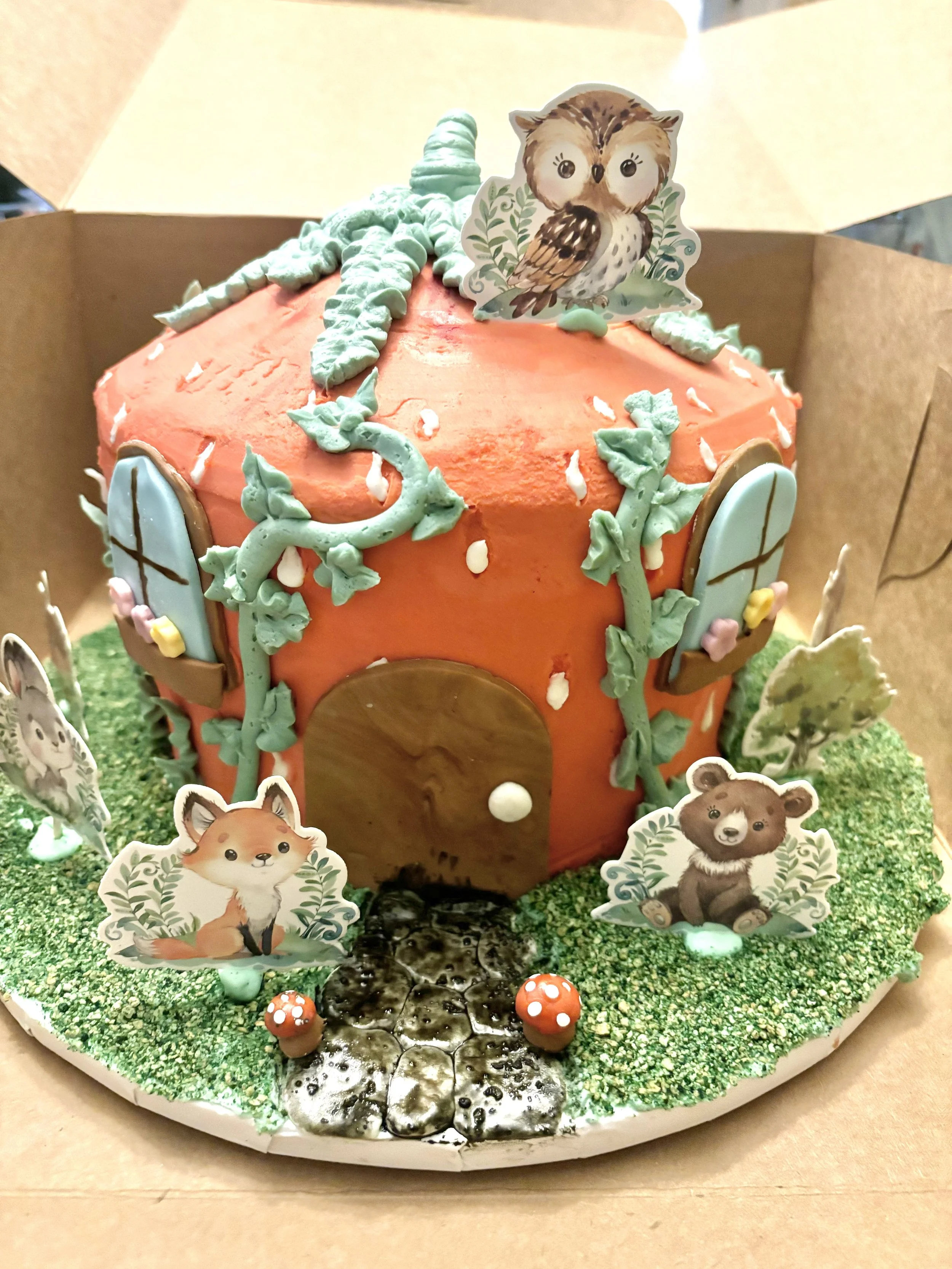 Whimsical strawberry house cake with woodland animals.