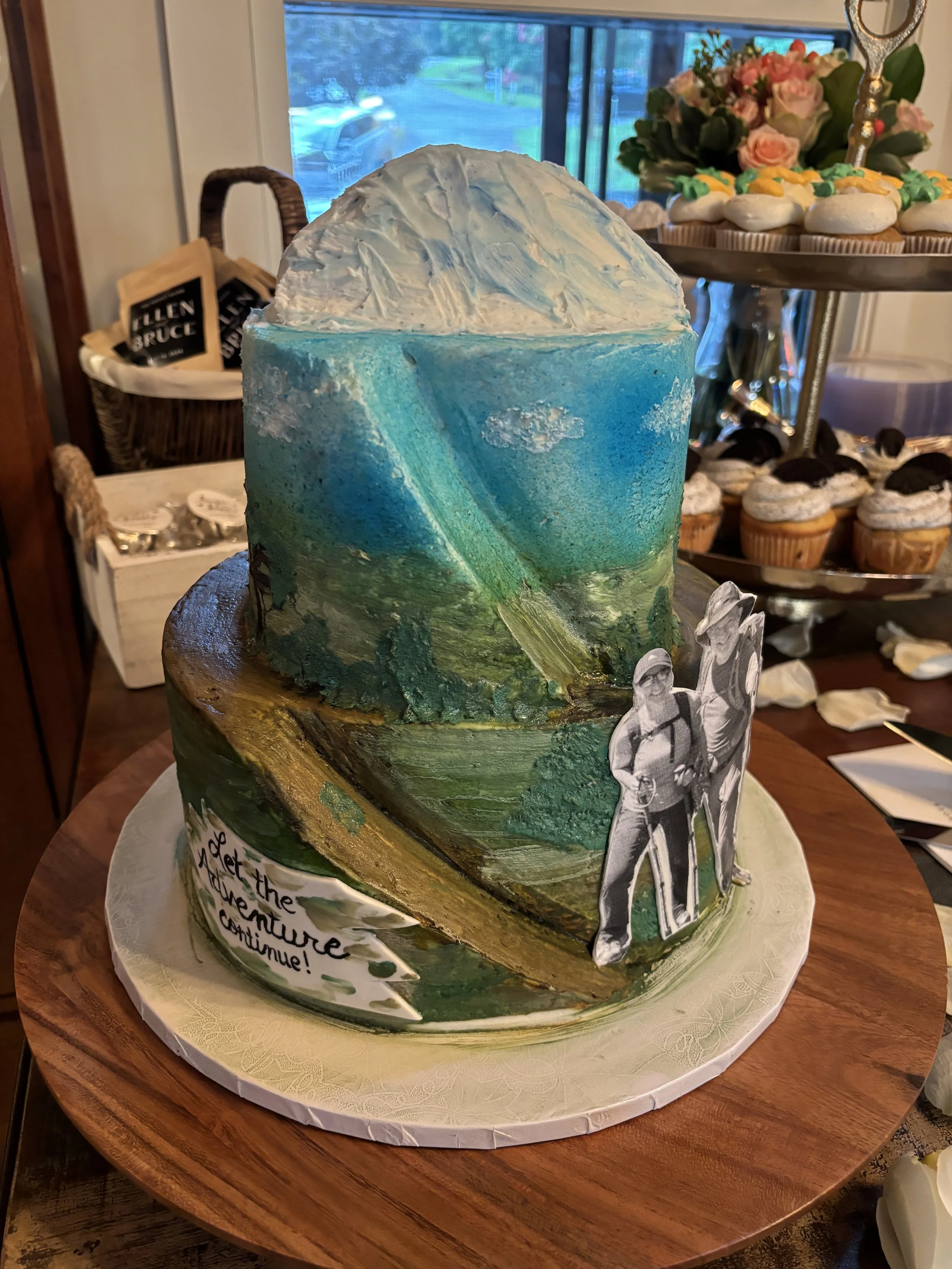 Two tiered cake with Mt. Kilimanjaro on top, a hiking trail going up the mountain, African terrain hand painted on