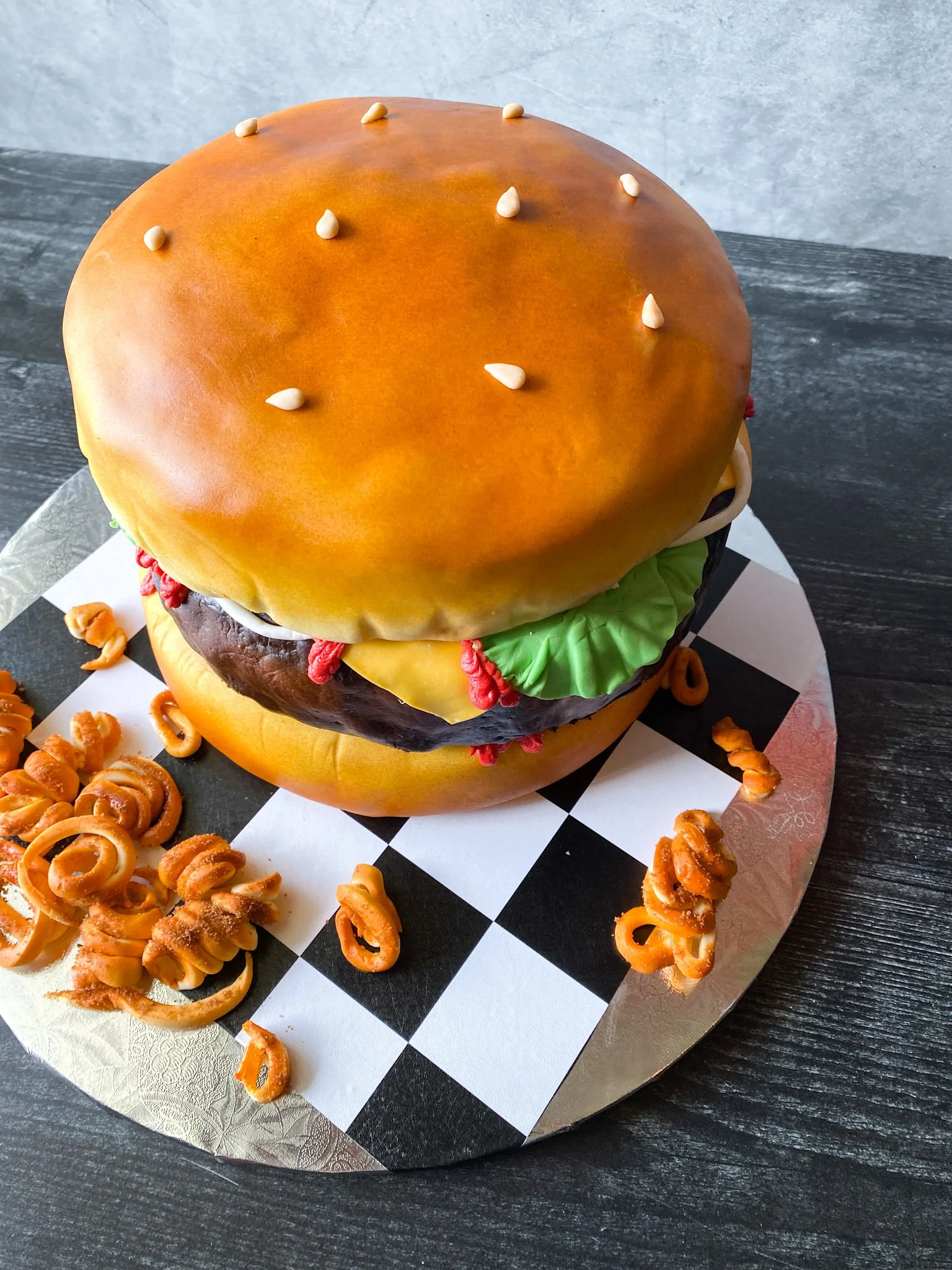 Cake shaped like a hamburger with sesame seeds and fondant curly fries