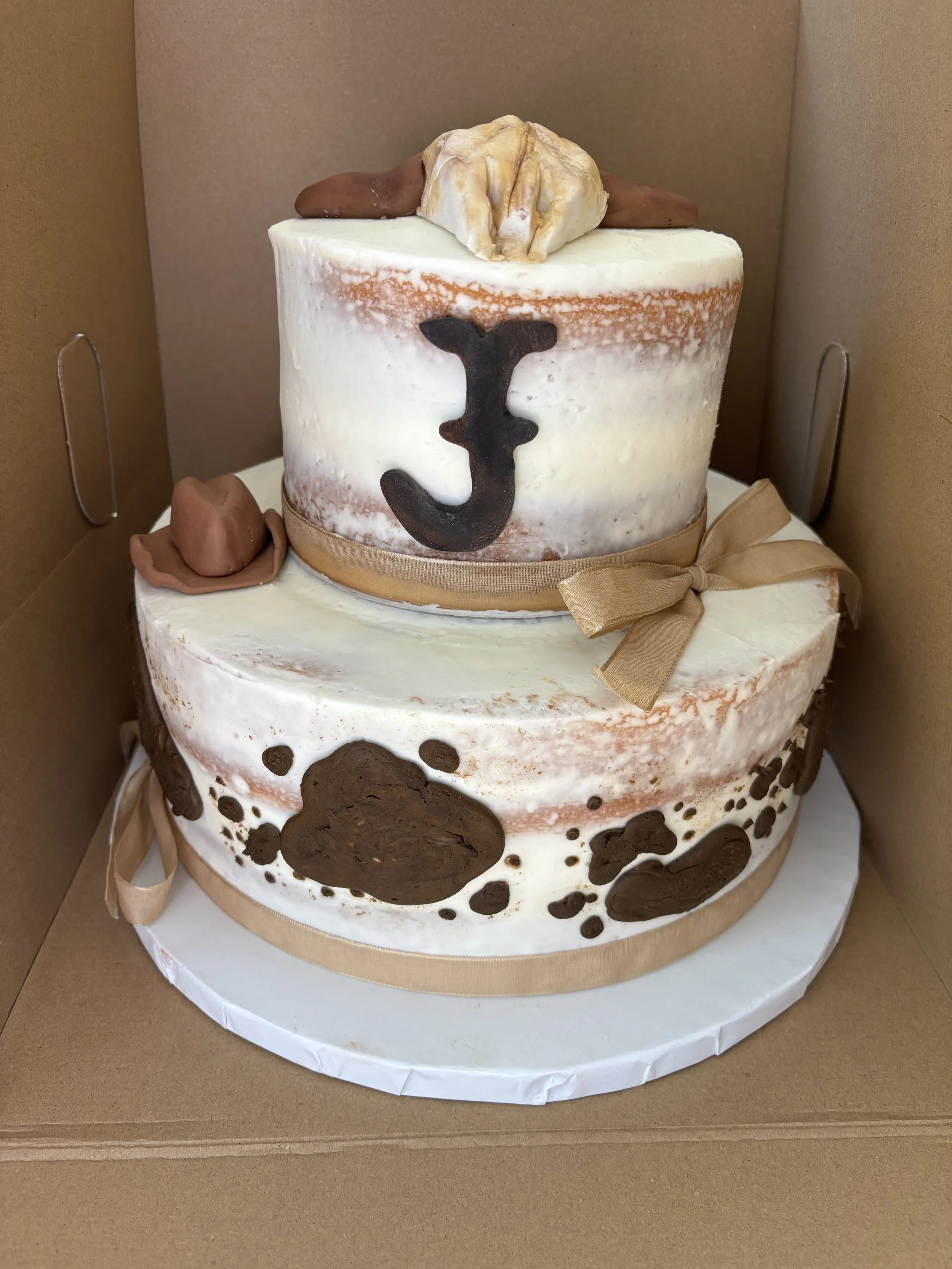 Western cowgirl cake with cow skull and cow print hat.