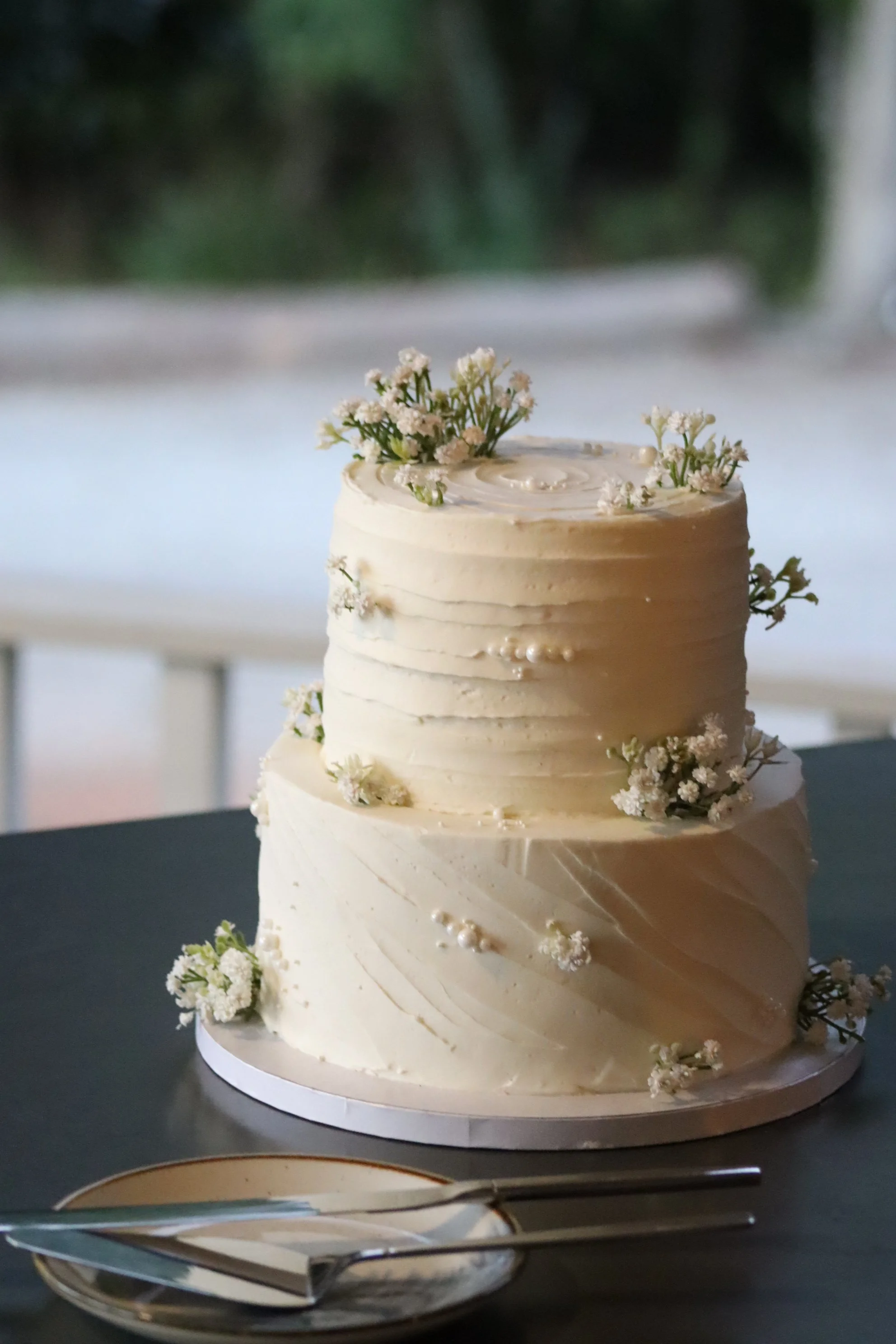 spatula iced buttercream wedding cake with artificial baby's breath and edible pearls