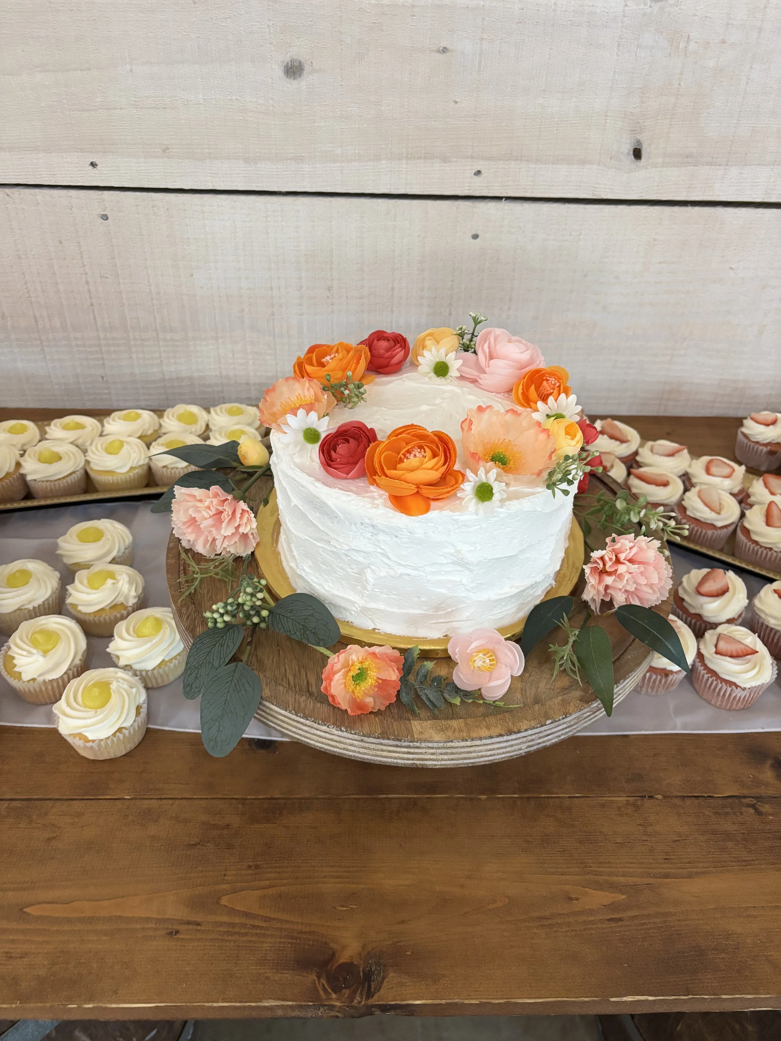 gluten-free and dairy-free wedding cutting cake with textured buttercream and bright flowers, surrounded by cupcakes at an Atlanta wedding