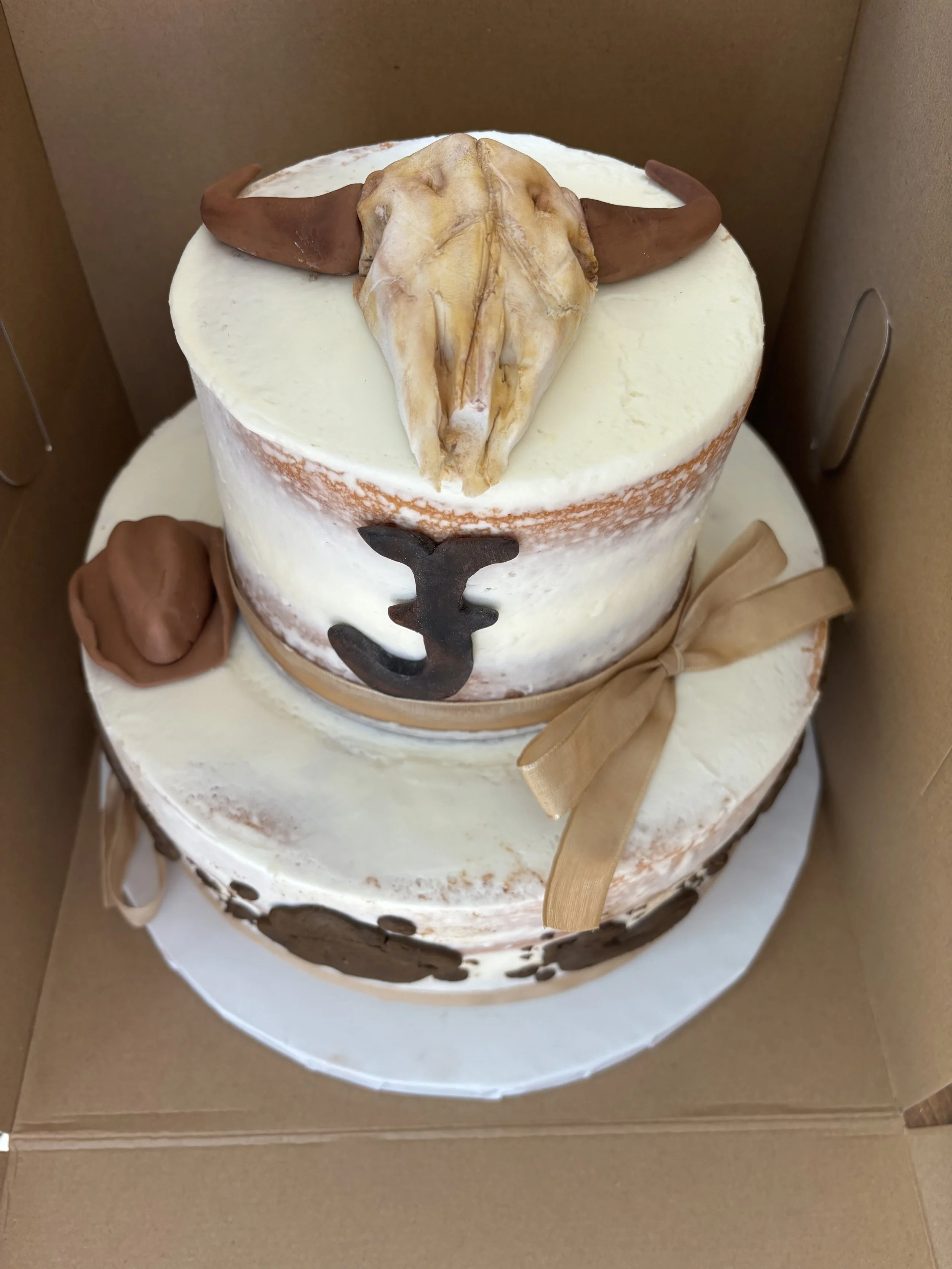 Western cowgirl cake with cow skull and cow print hat.