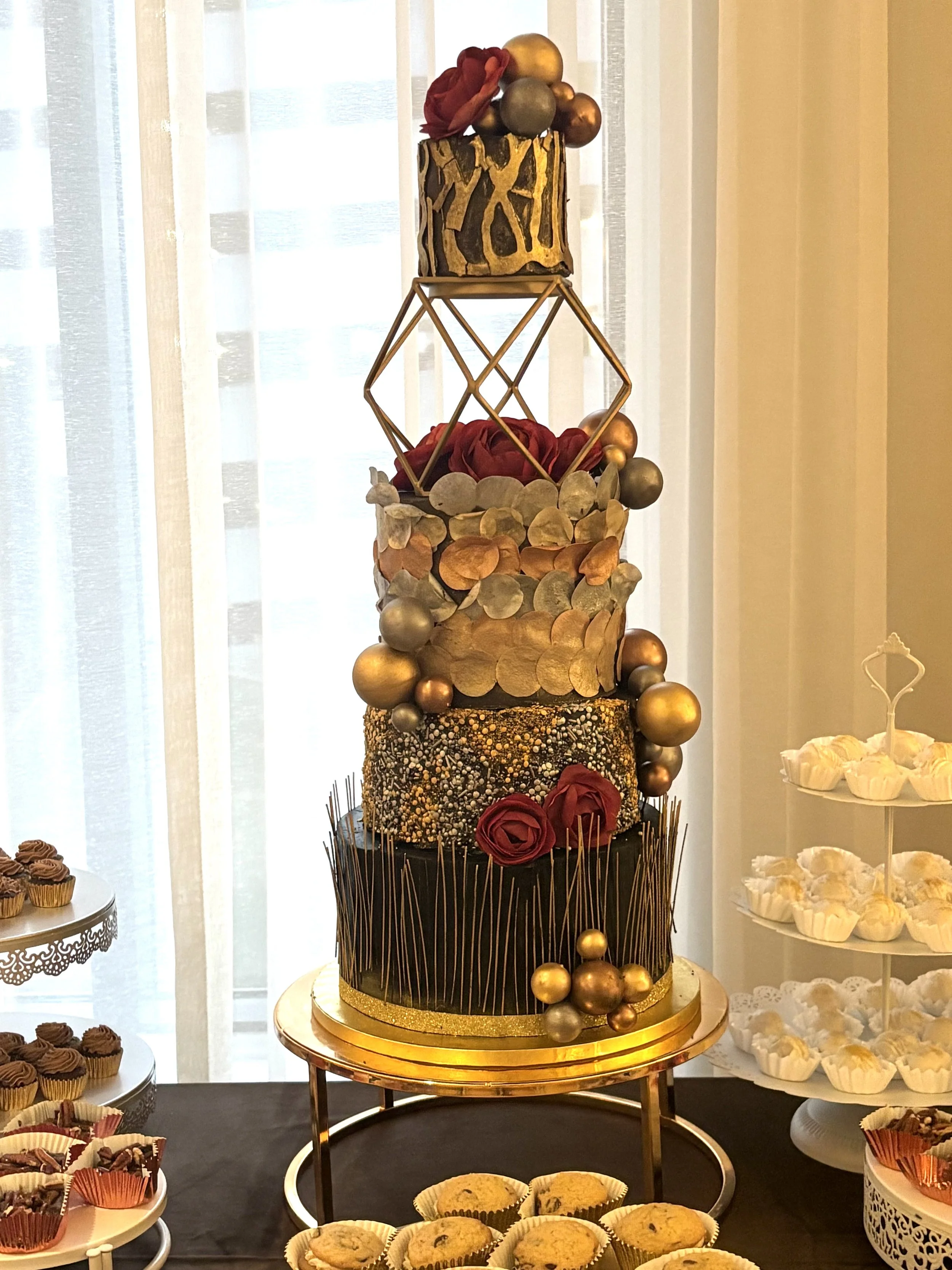 Tall sculptural faux cake by Artful Cakery by Julie with metallic gold accents, textured tiers, and deep red florals, designed for the Atlanta Style Weddings 2026 launch party in Atlanta, Georgia.