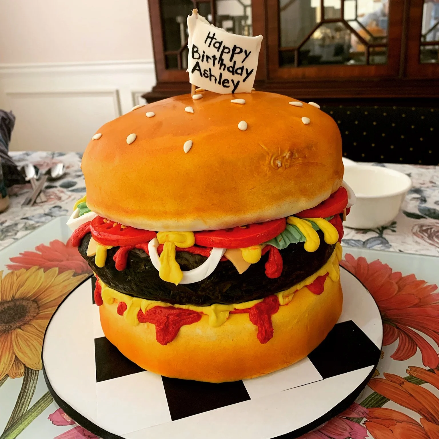 Realistic cheeseburger illusion cake sculpted and decorated to resemble a freshly made burger.